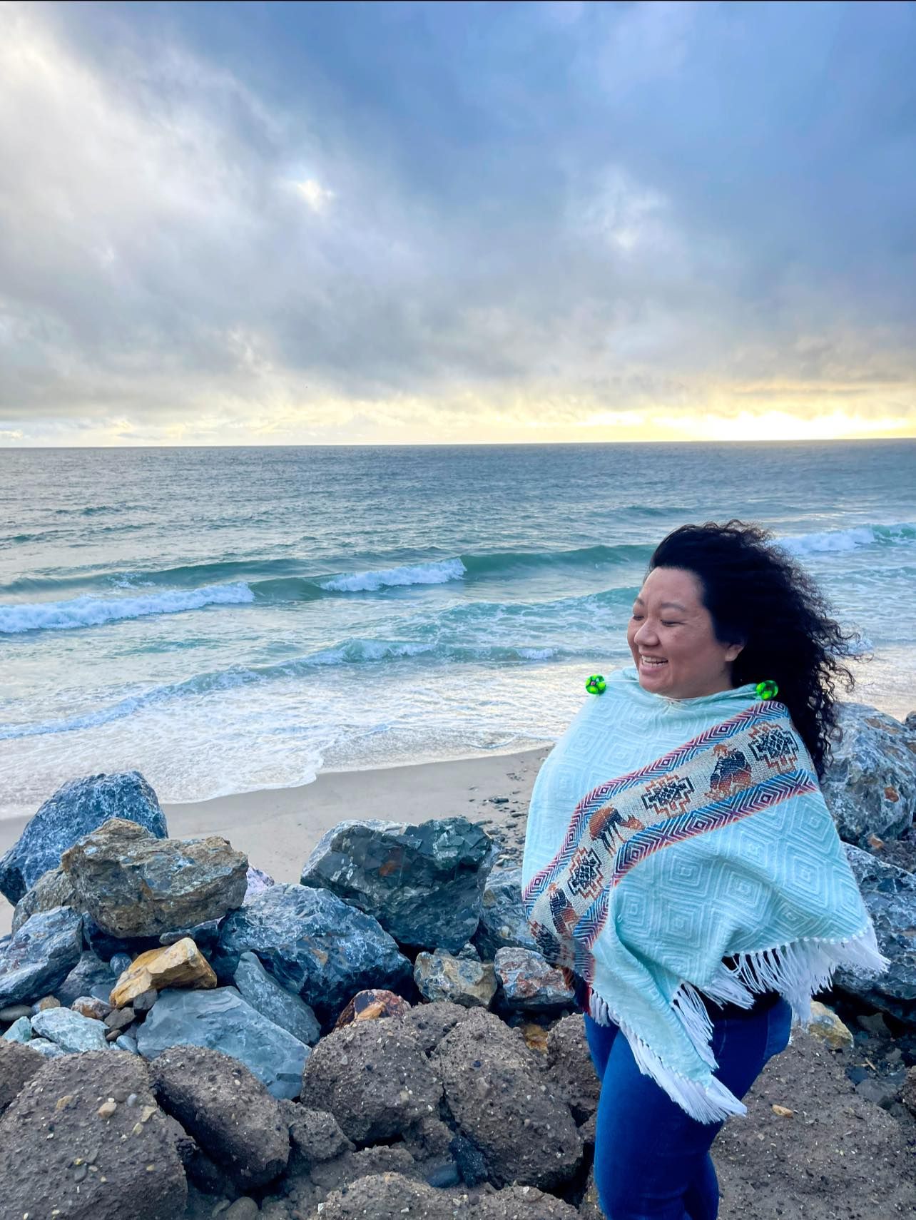 Artistic sequence of poses against ocean backdrop with blue flowing fabric in the wind.