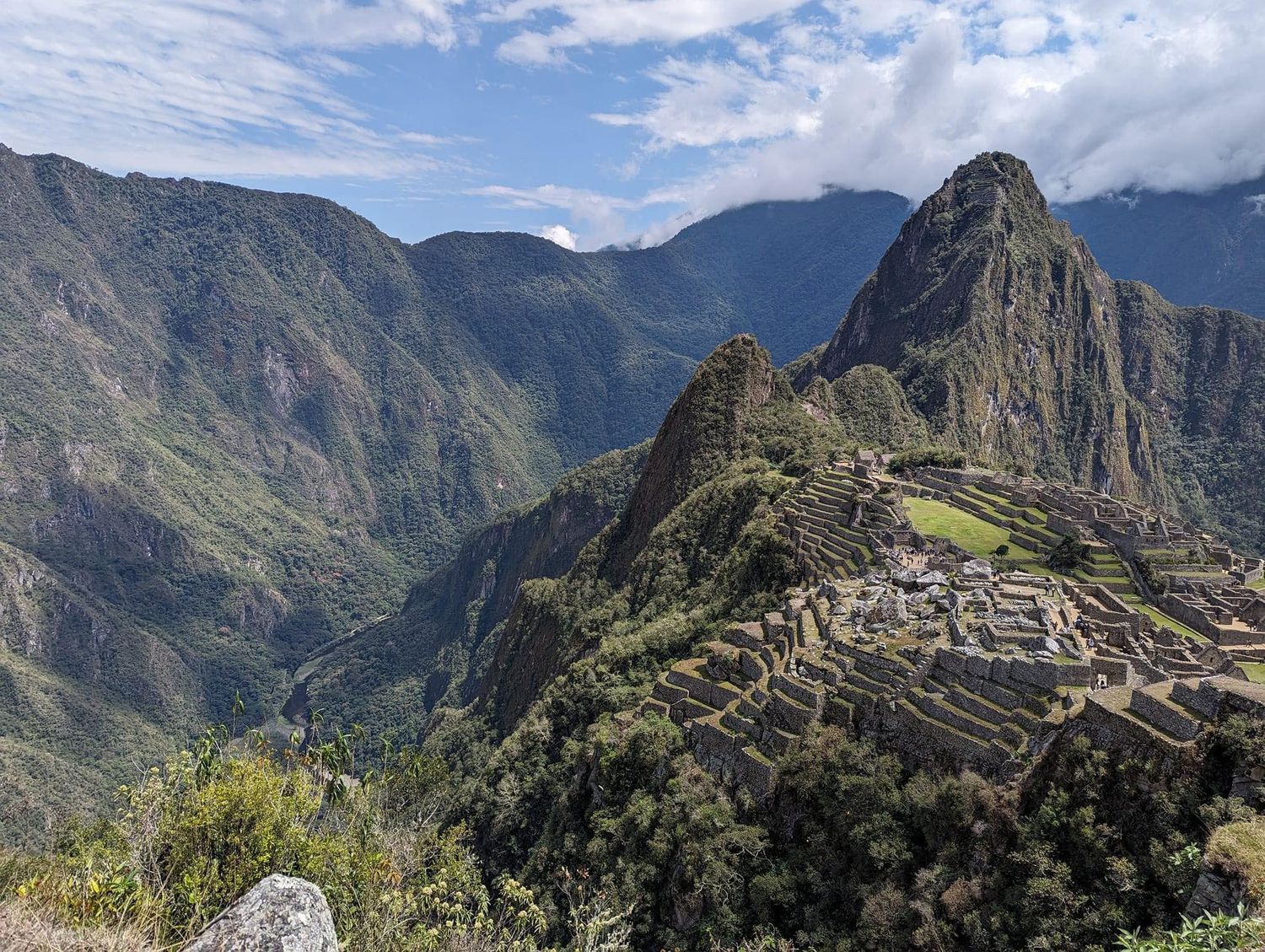 Ancient Incan ruins of Machu Picchu nestled among green mountain peaks under blue skies.