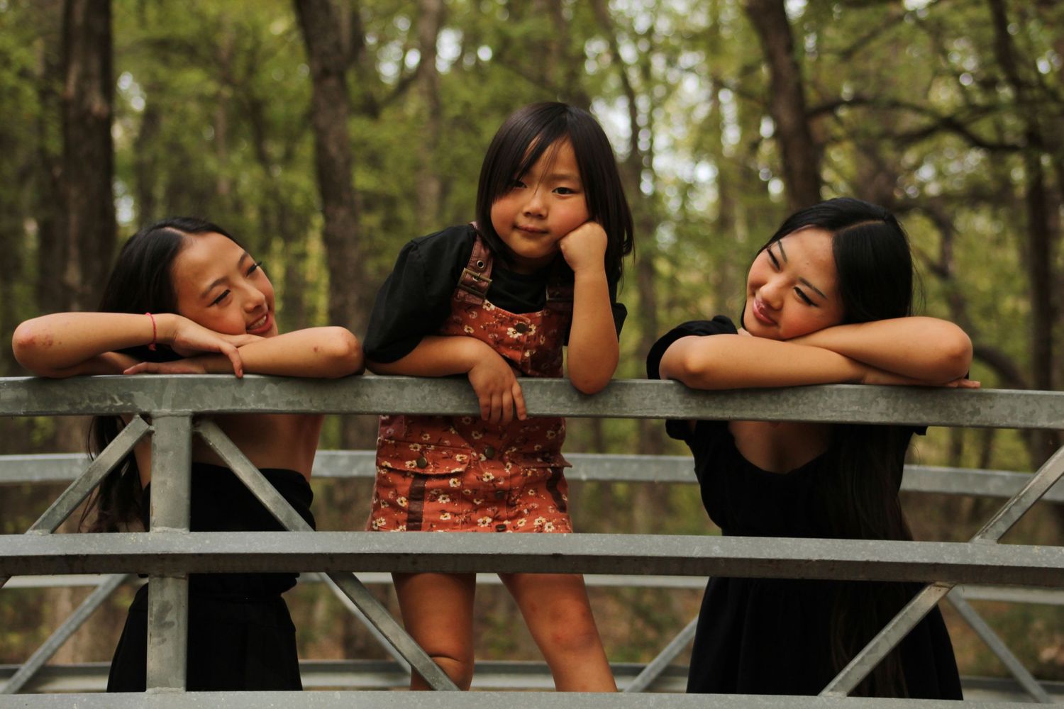 Friends relaxing and chatting while sitting on a wooden railing in a park.
