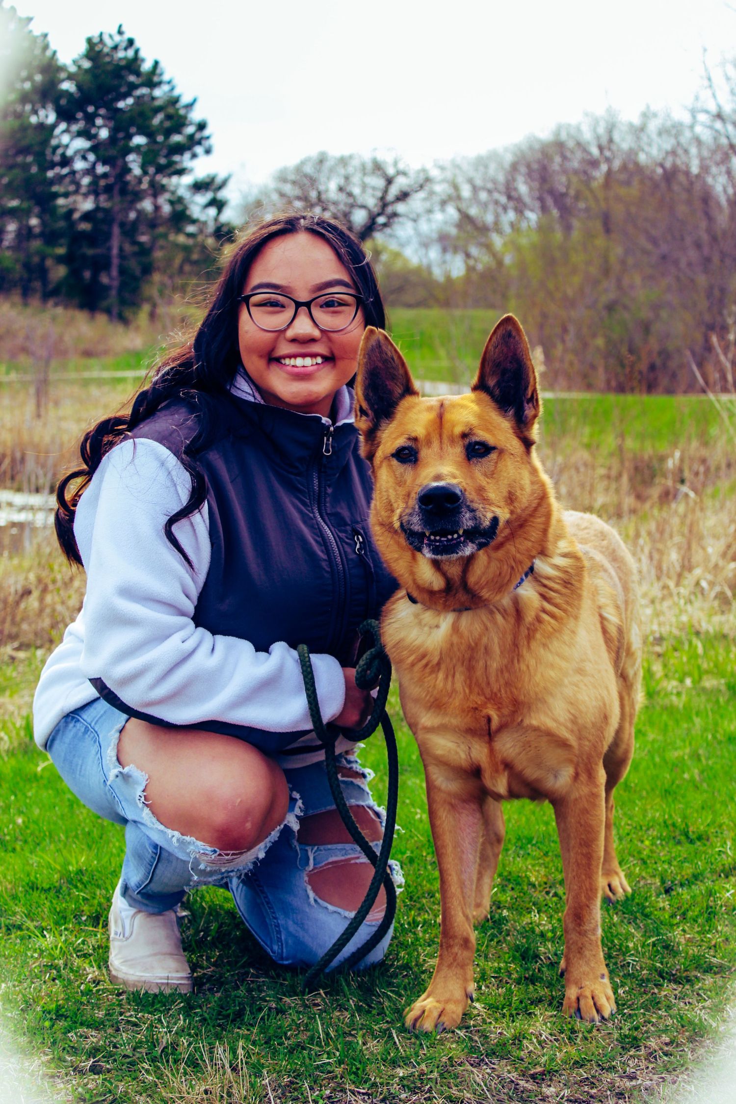 Portrait series with a friendly brown dog and their owner in an outdoor field setting.