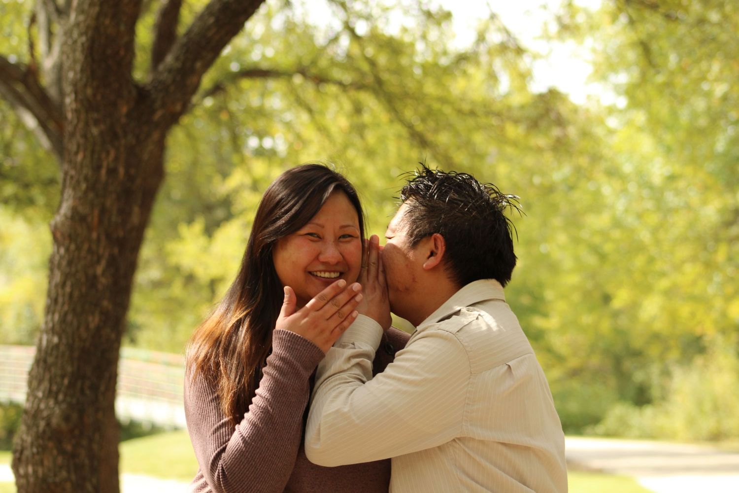 A romantic moment captured between a couple in a sunlit park.