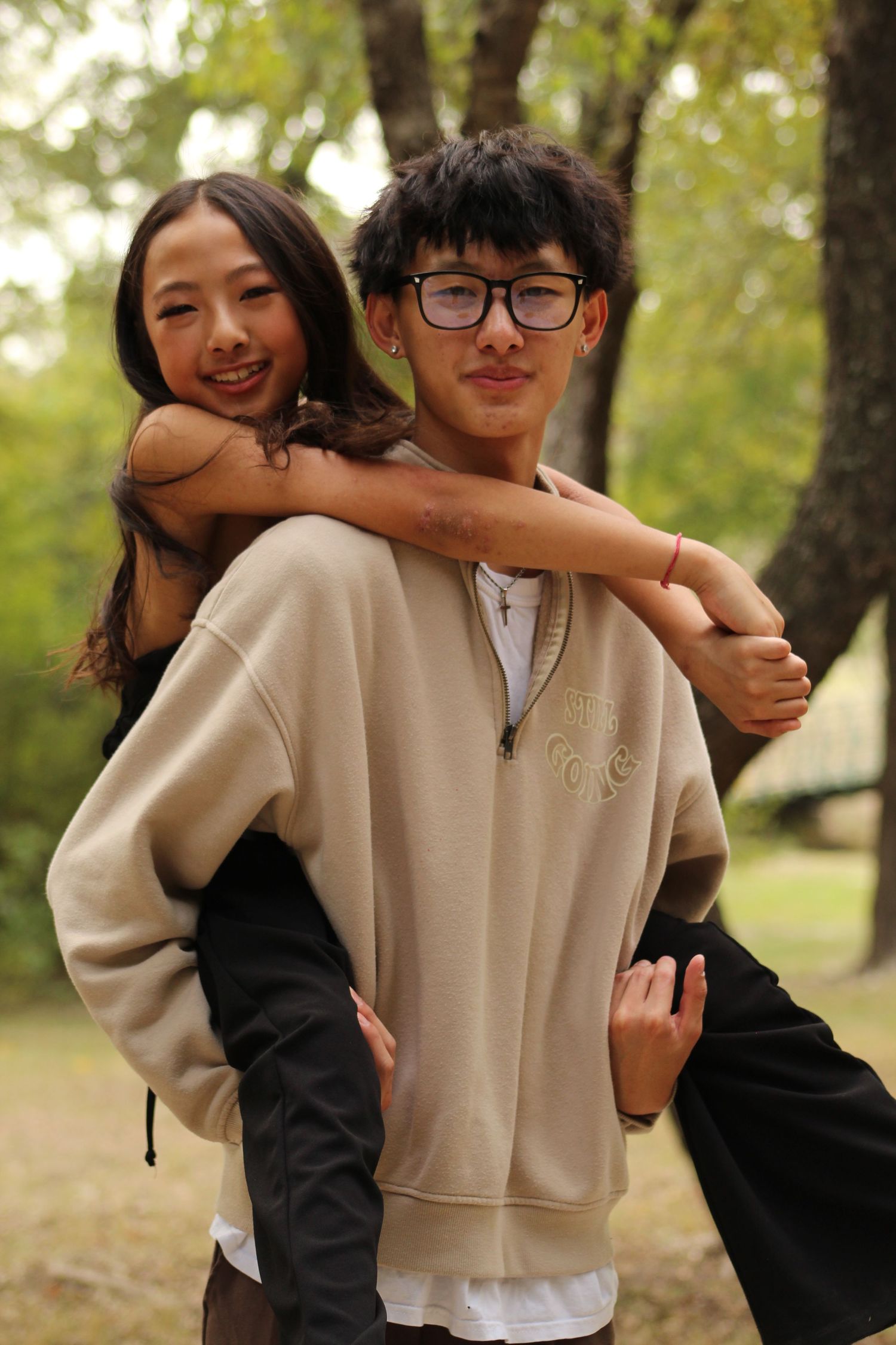 A playful outdoor photoshoot in a park with people wearing black and beige outfits.