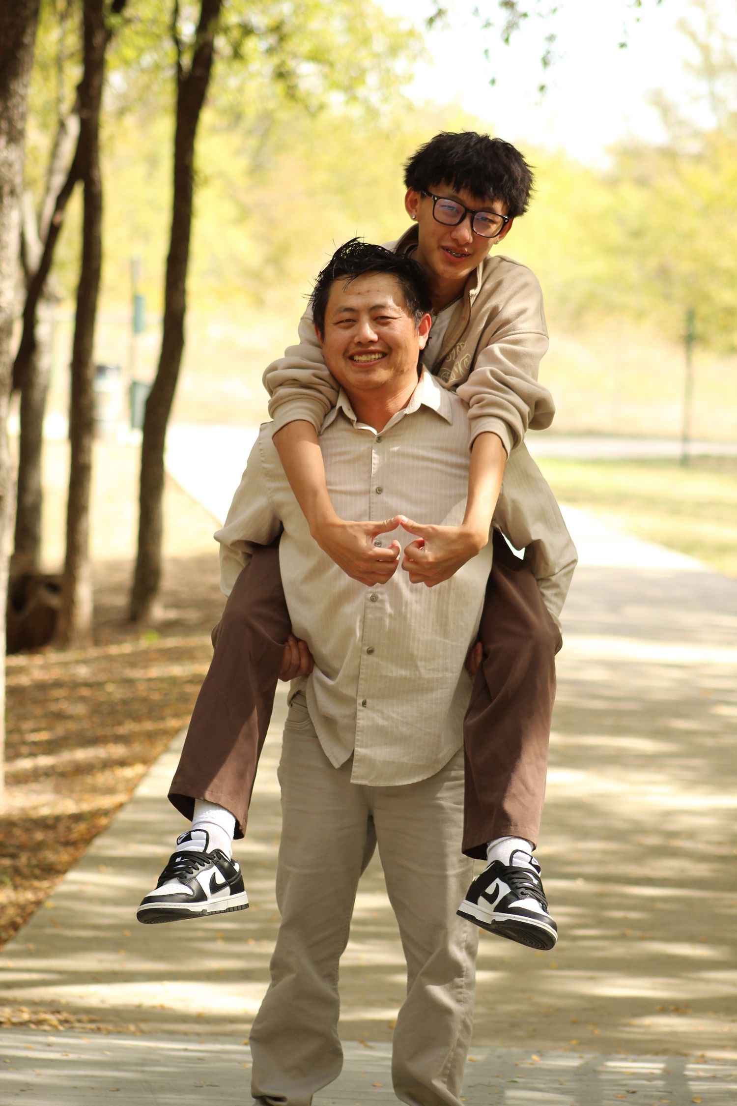 Playful piggyback ride sequence captured on a tree-lined path.