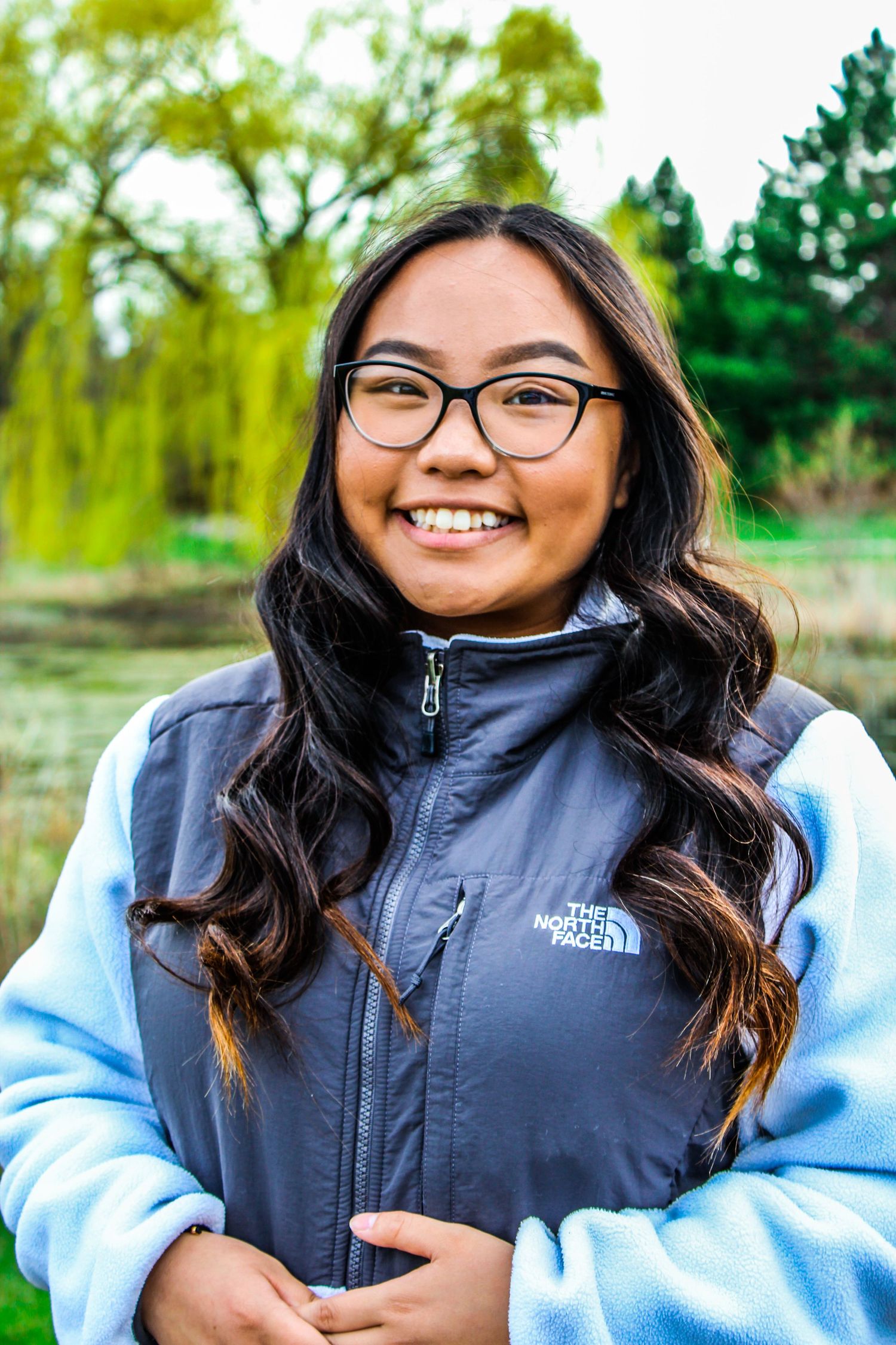 Outdoor portrait series showing someone in a North Face vest and light blue sweater.