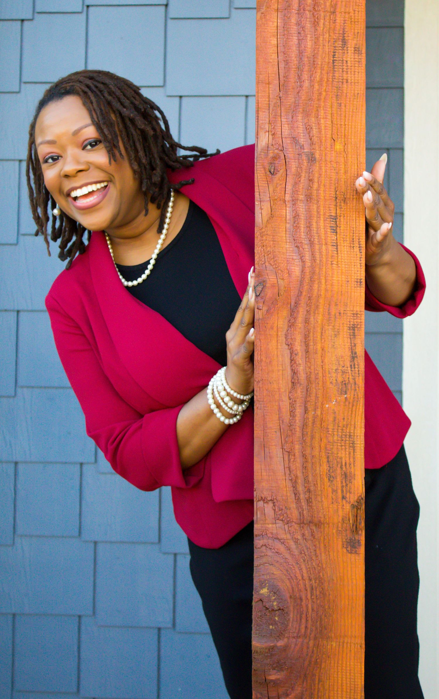 Playful portrait series showing someone in red and black peeking around a wooden post.