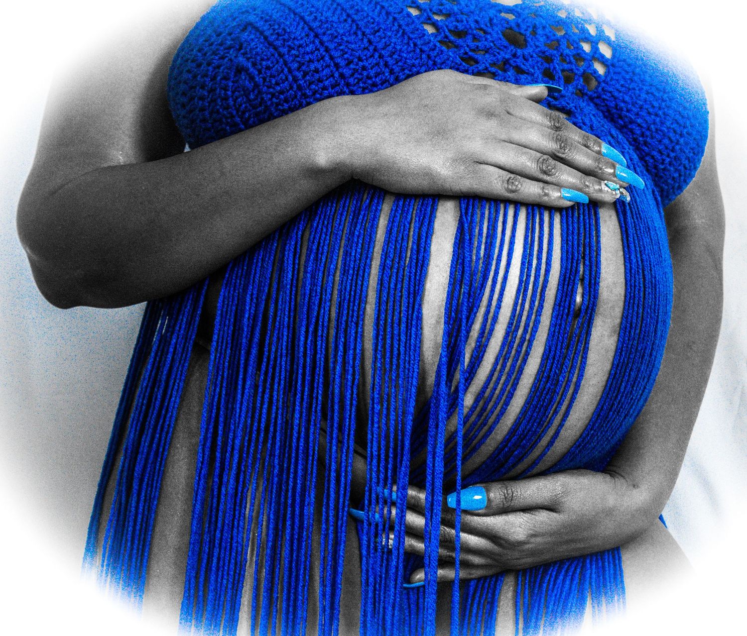 Close-up detail of royal blue crochet work and long fringe against contrasting background.