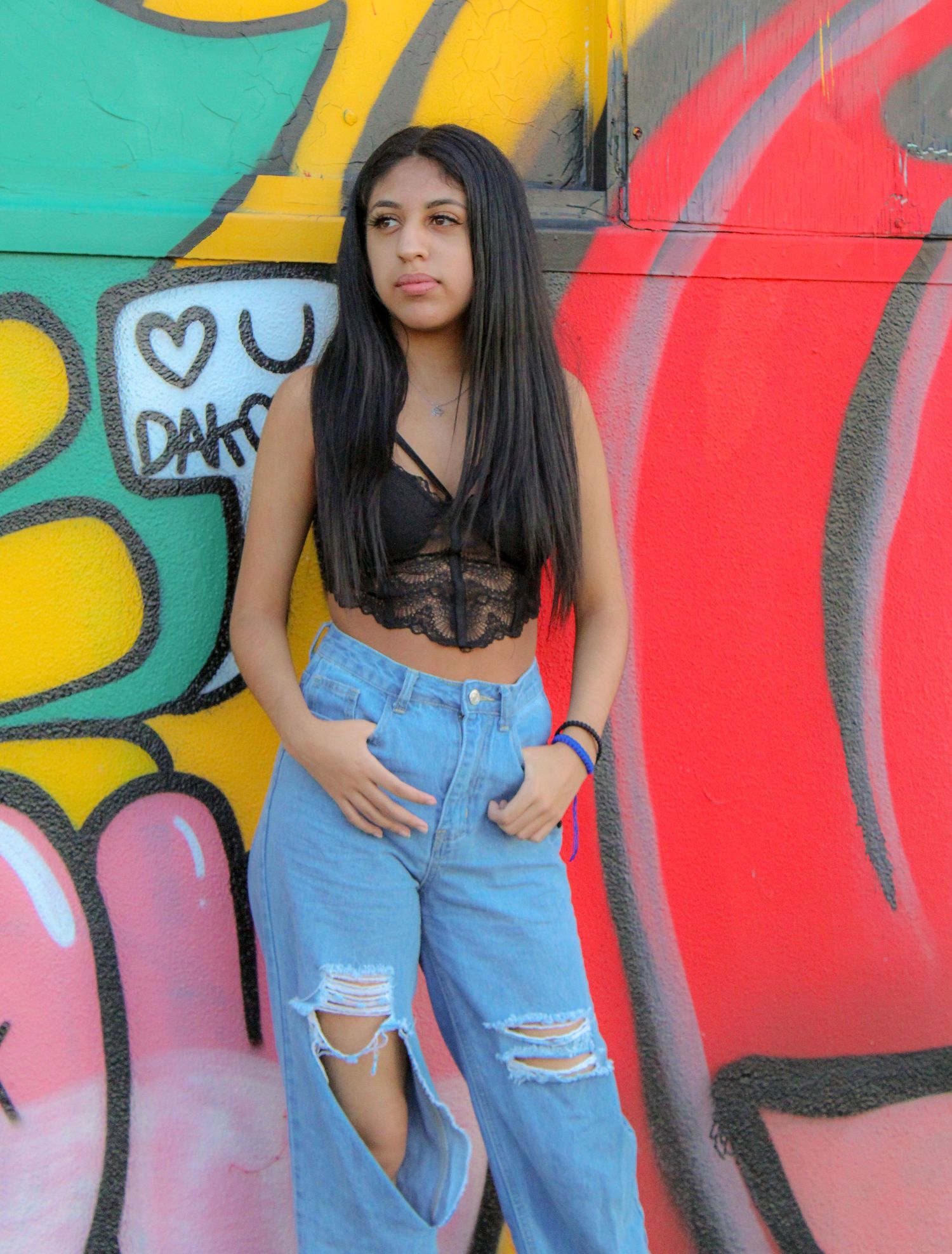 Vibrant graffiti wall serves as backdrop for casual street style photography.