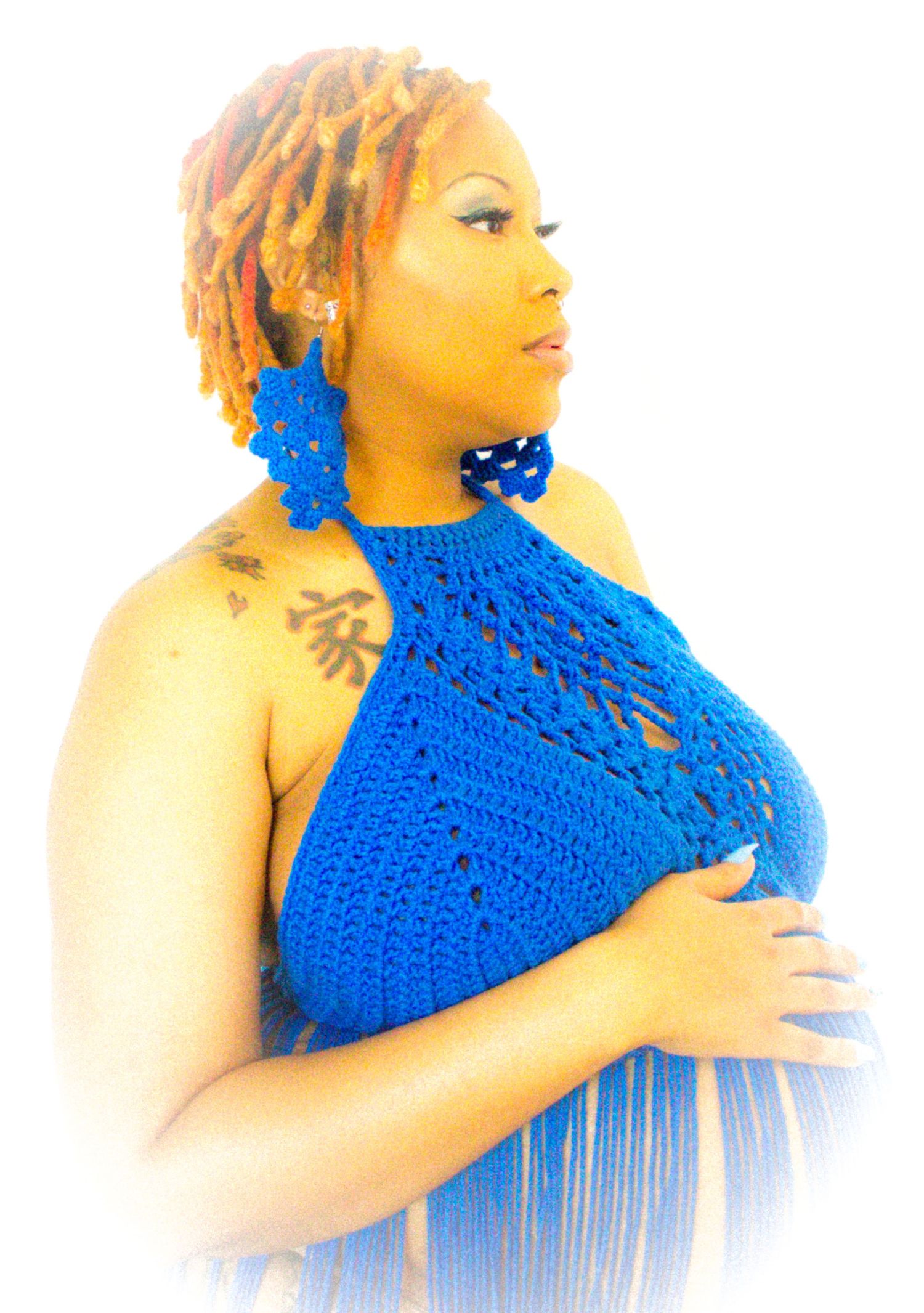 Side profile maternity portrait in bright blue crochet halter top.