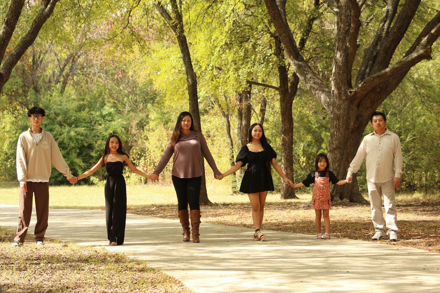 People walking along a scenic path under trees with golden sunlight filtering through.