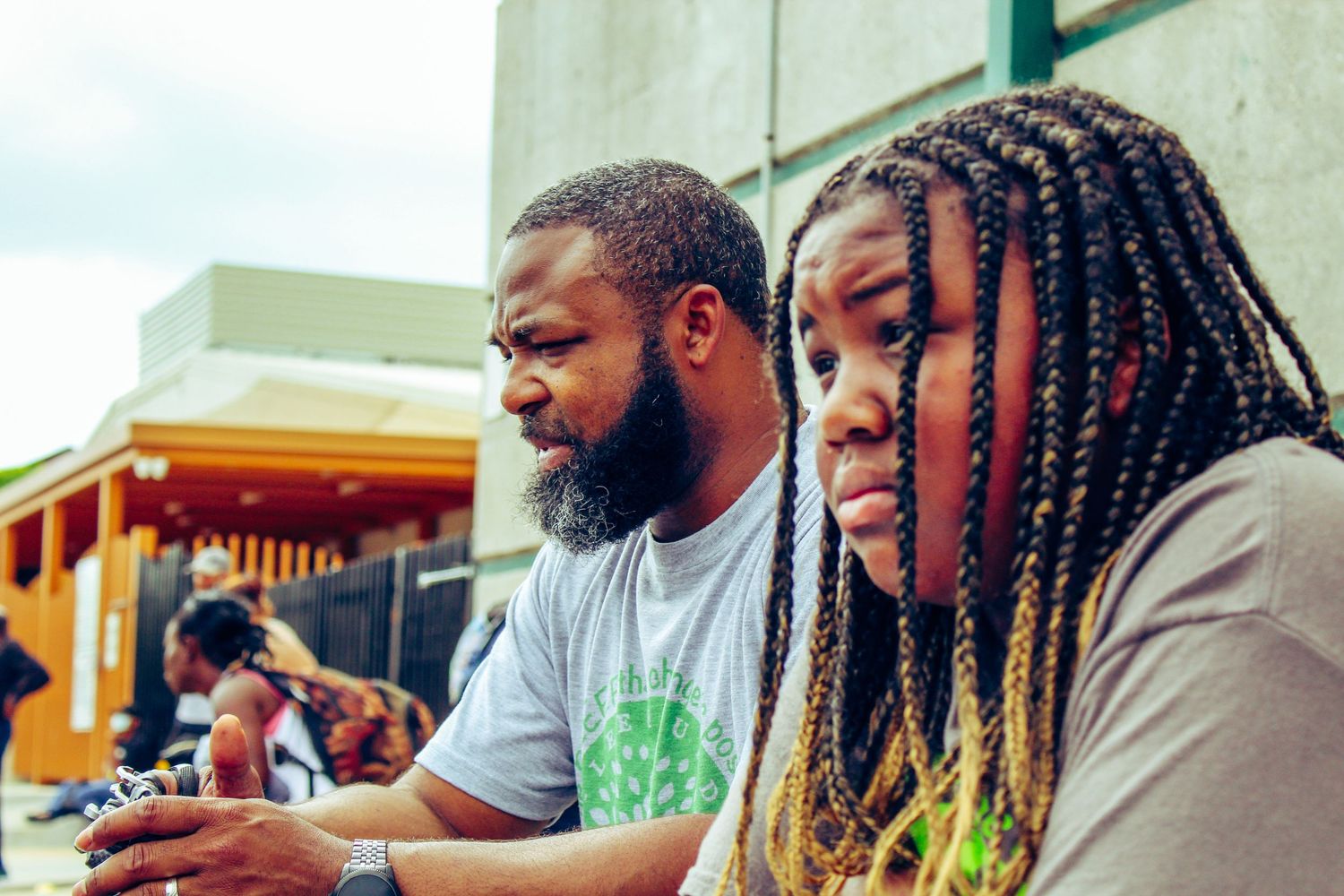 Two people seated at an outdoor table near a building.