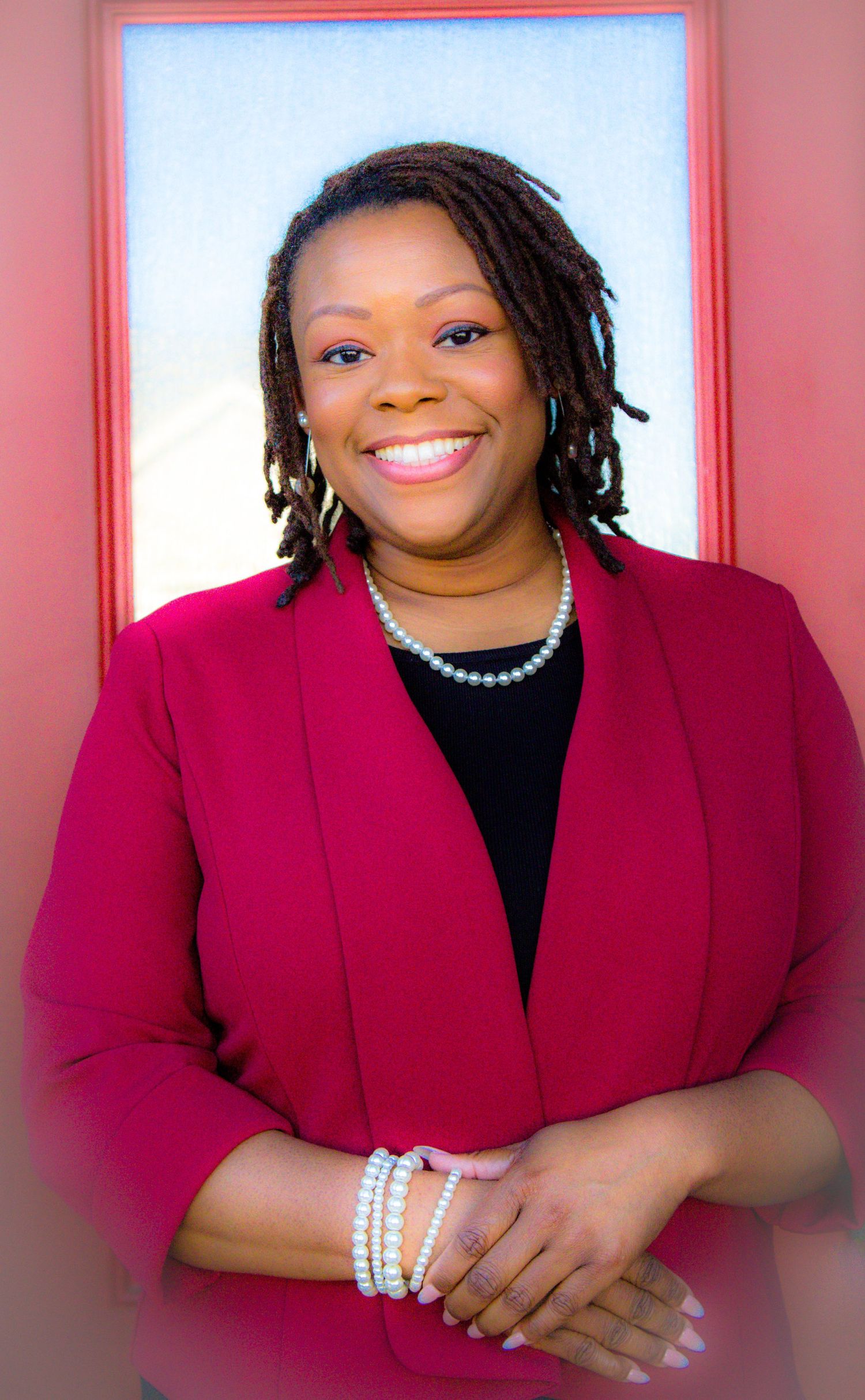 Professional portraits in red blazer against pink and blue background.
