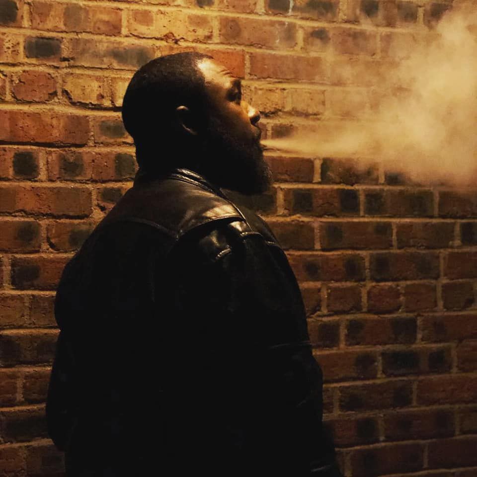 Atmospheric shots against a brick wall with steam or smoke creating a moody effect.