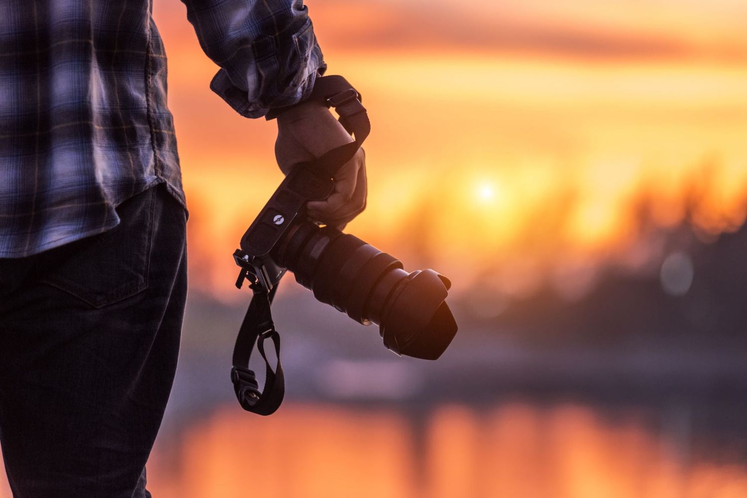 Camera equipment silhouetted against a vibrant orange sunset sky.