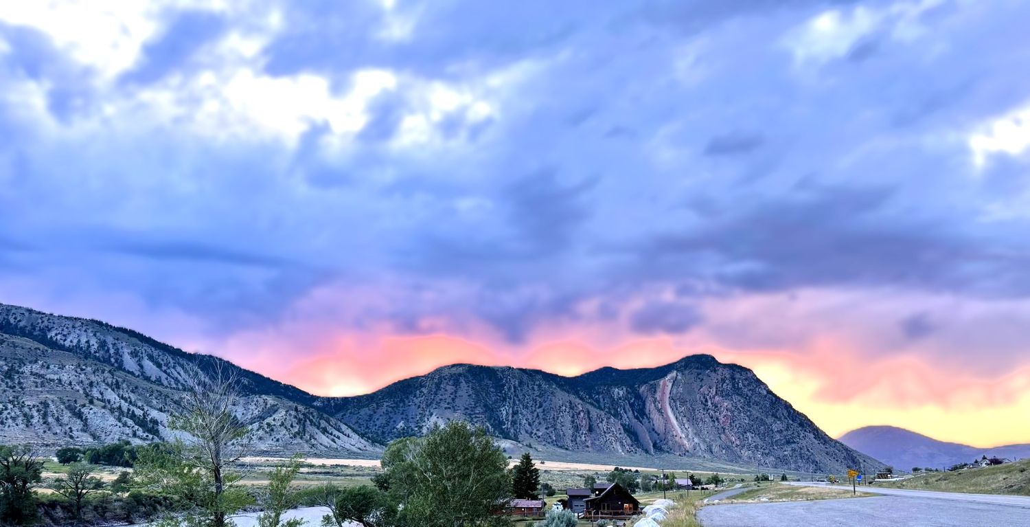 Majestic mountain peaks under a moody blue sky with wispy clouds during sunset.