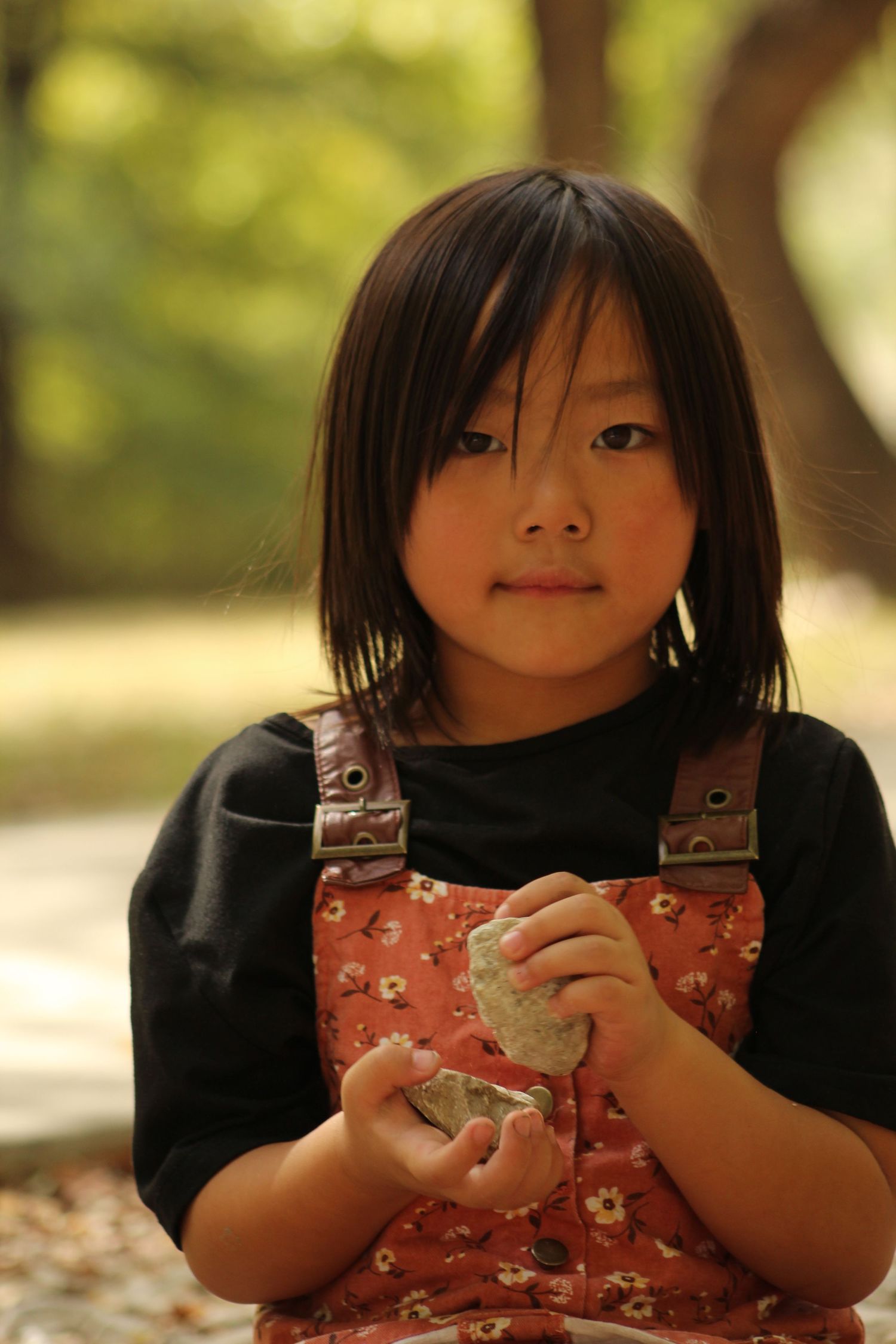 Close-up sequence of a child holding something while wearing floral overalls.