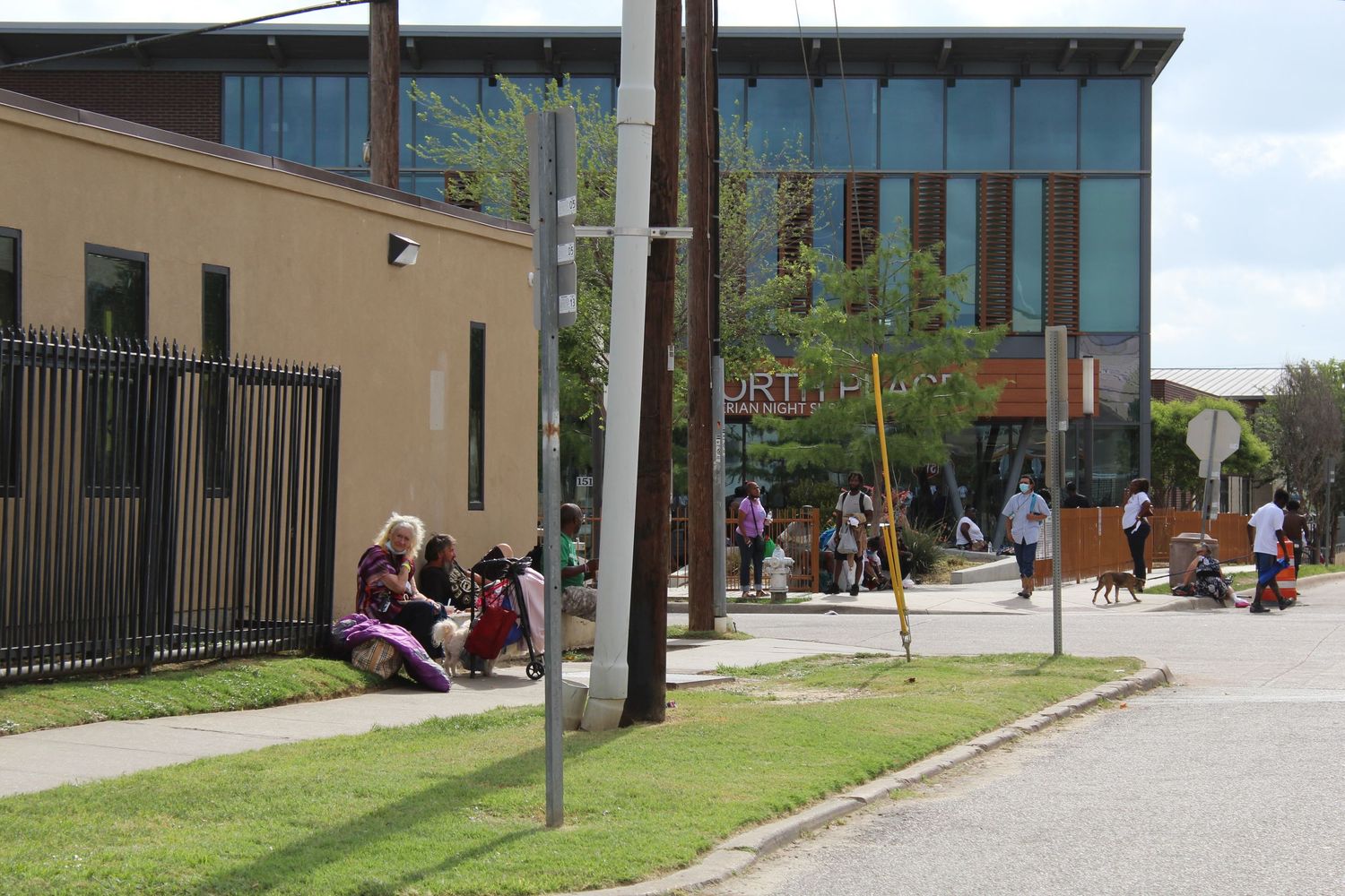 Modern building exterior with glass windows and metal fencing along a paved street.