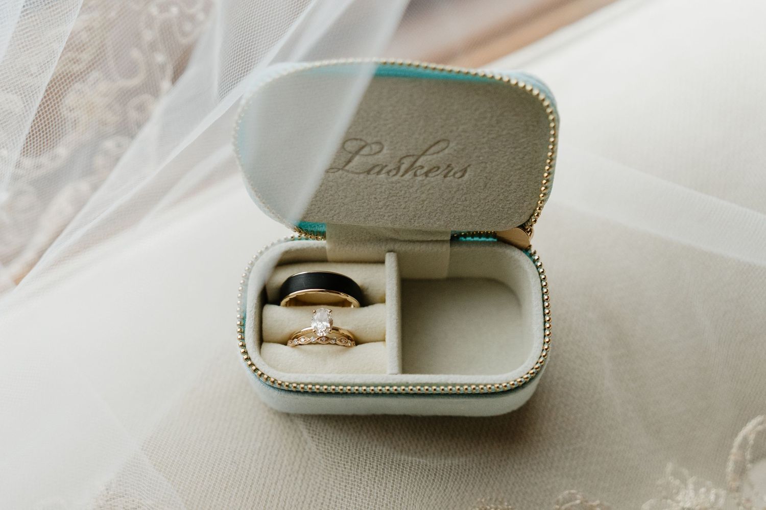 Two wedding rings displayed in an open mint green Lashers jewelry travel case.