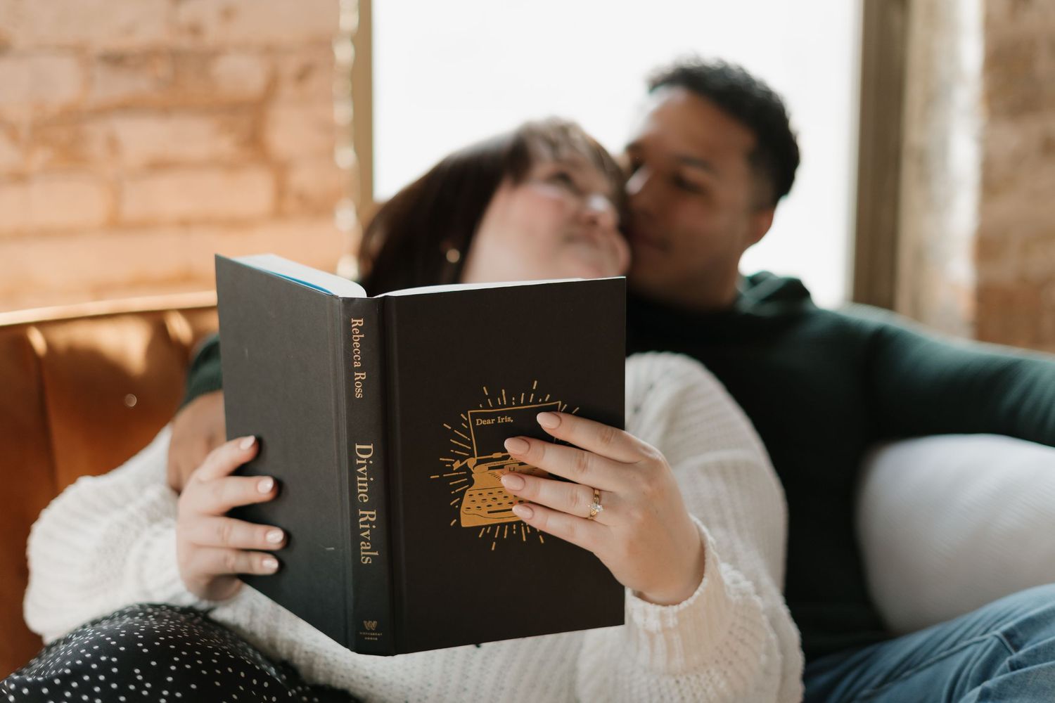 Couple relaxing together on a couch, woman holding a Holy Bible book in the foreground.