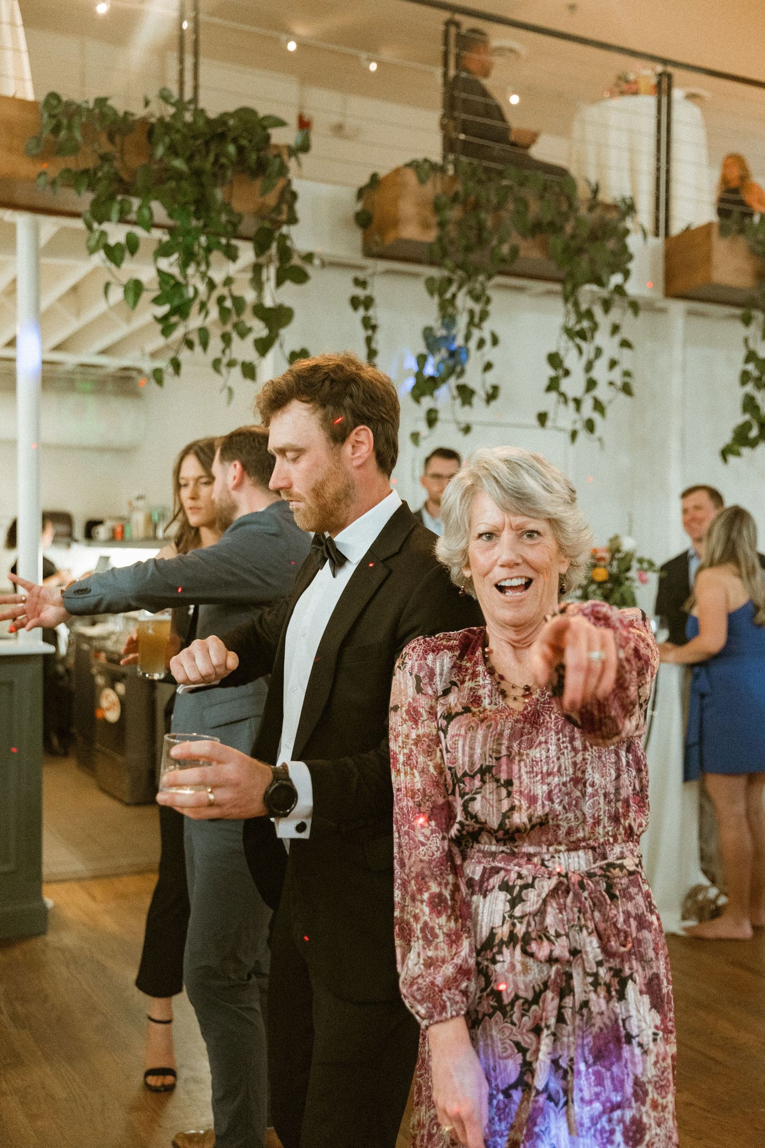 Wedding guests enjoying drinks and dancing in a decorated indoor venue.