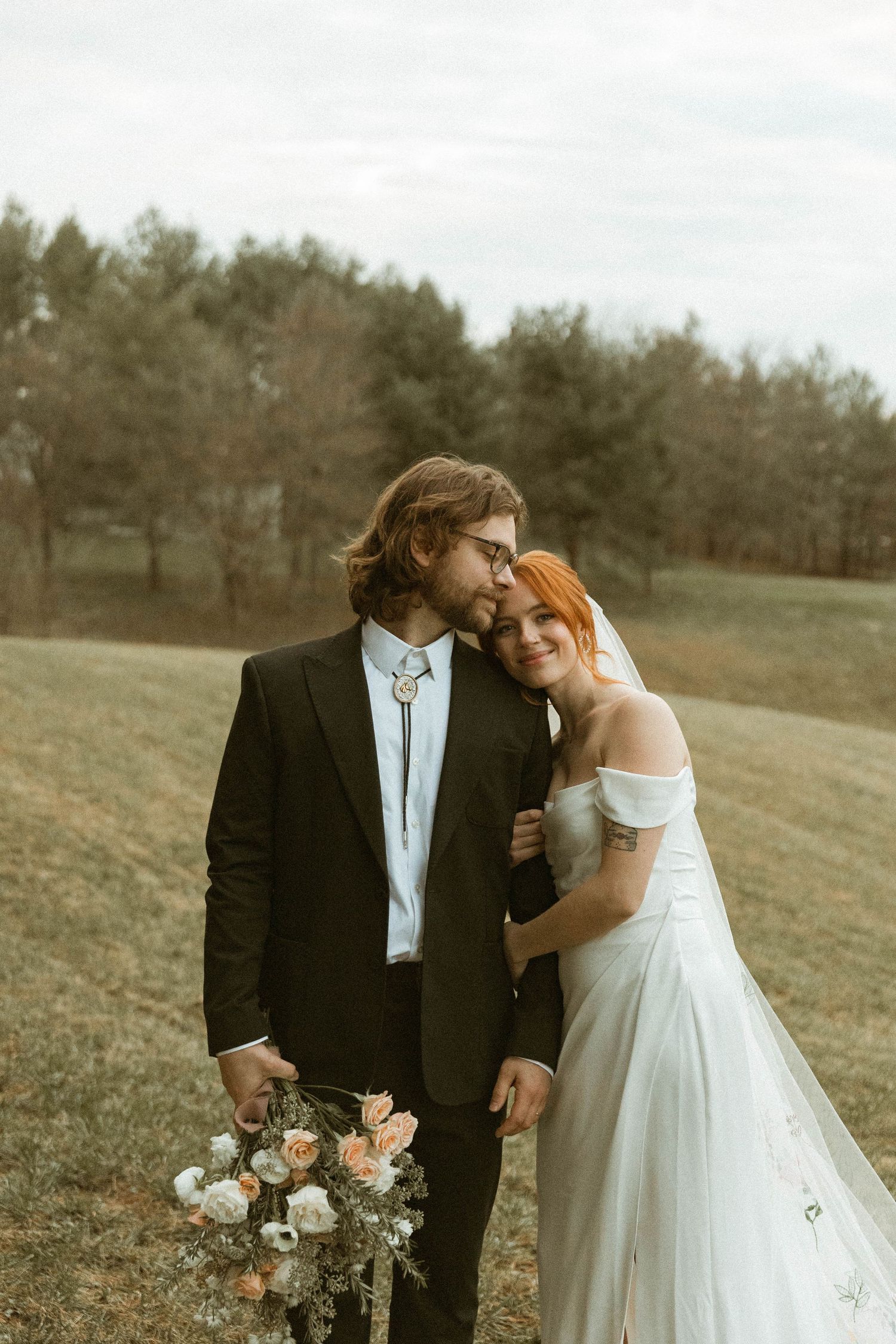 A bride and groom share an intimate moment in a field during golden hour photography.