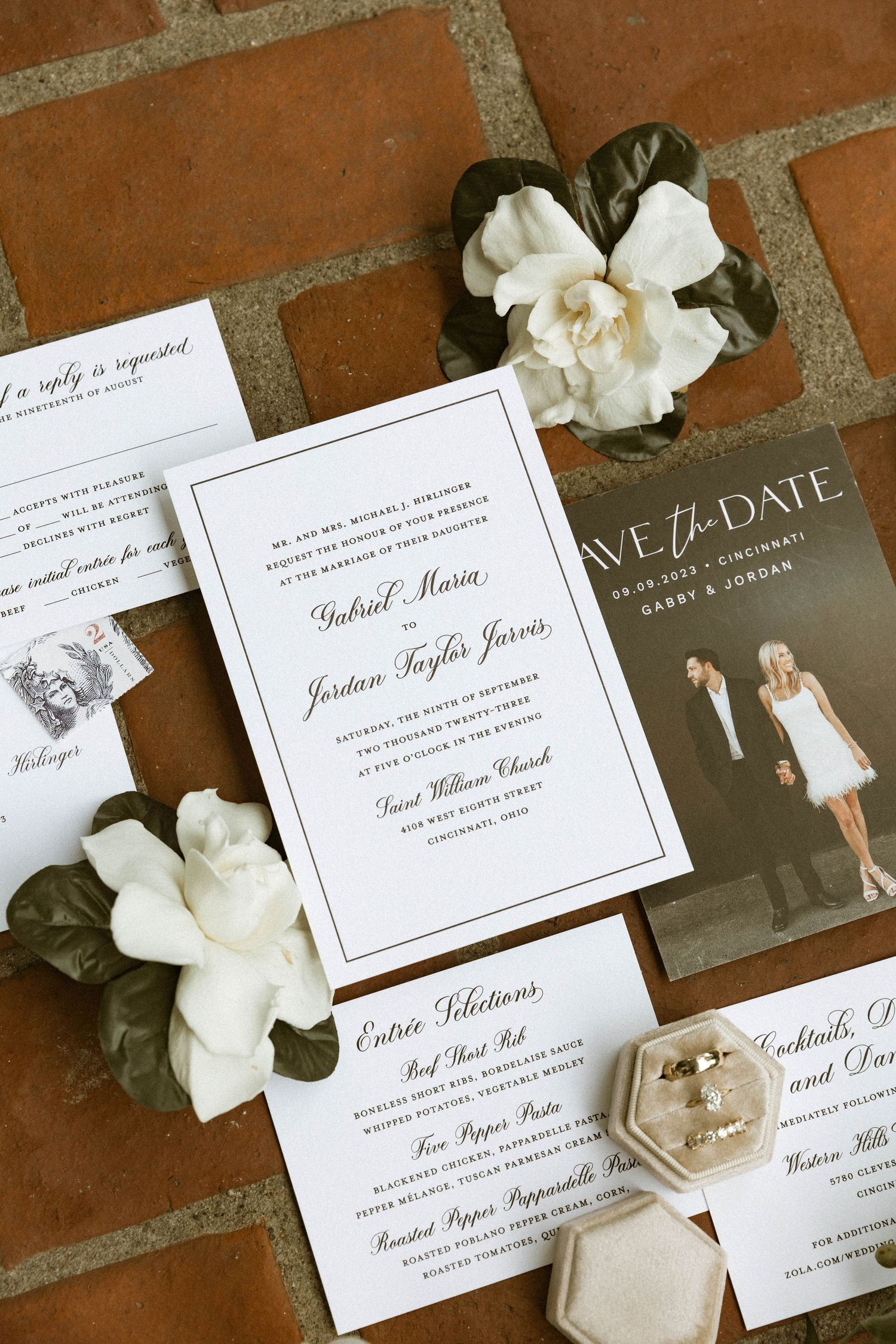 Elegant wedding invitation suite with white flowers and save the date card on terracotta tiles.