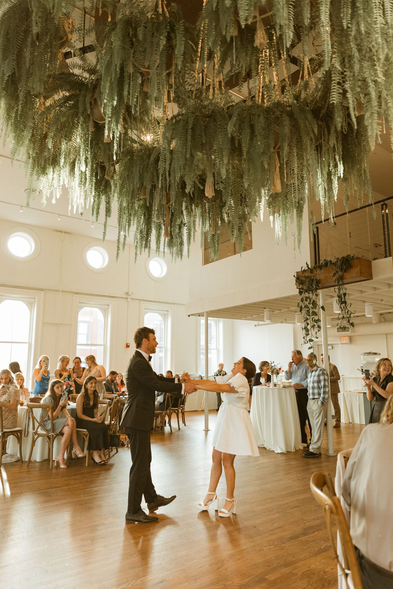 Wedding celebration in a modern venue with dramatic hanging moss decor and guests.