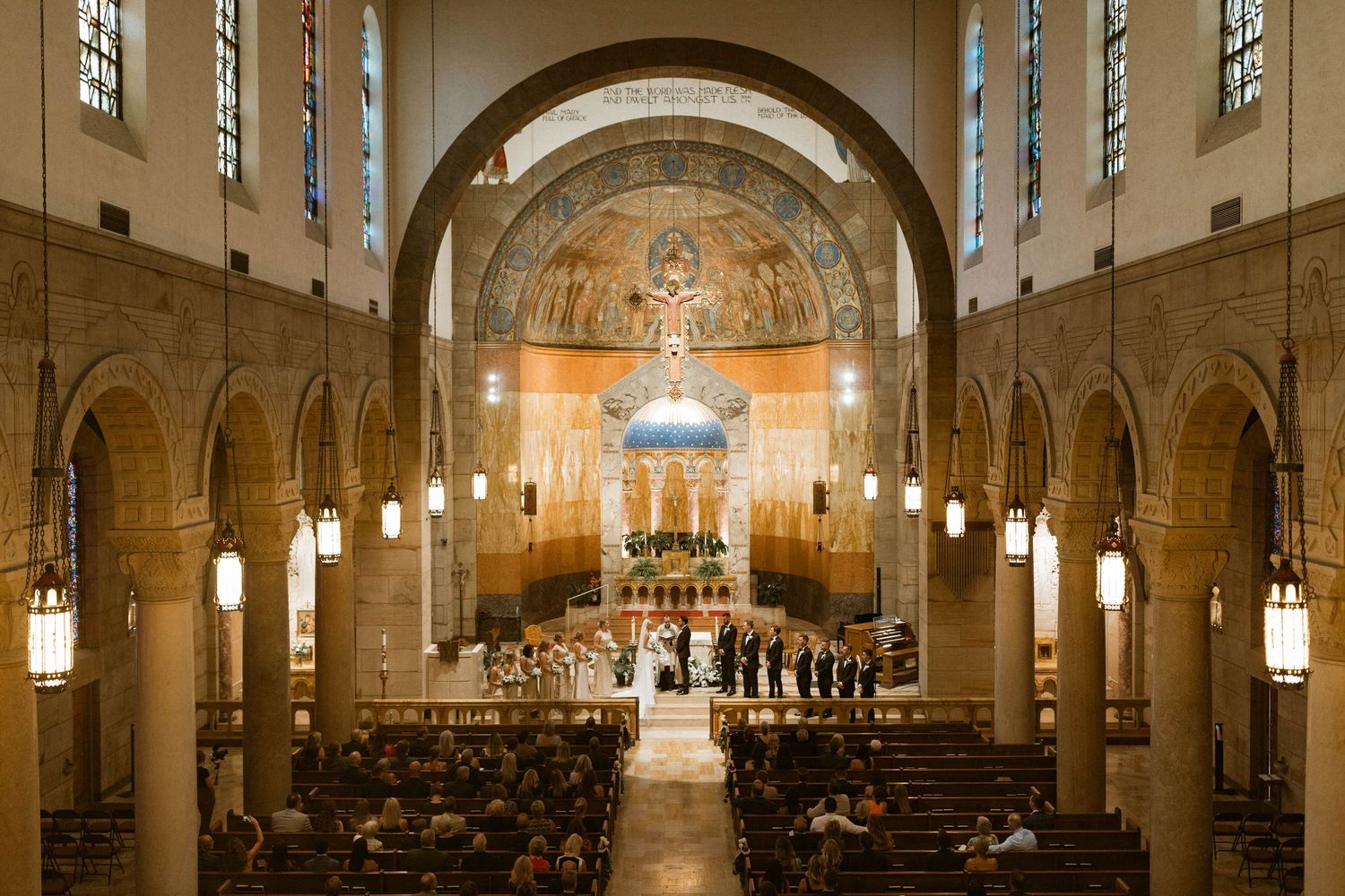 Interior of a grand cathedral with arched ceilings and elegant lighting during a wedding ceremony.