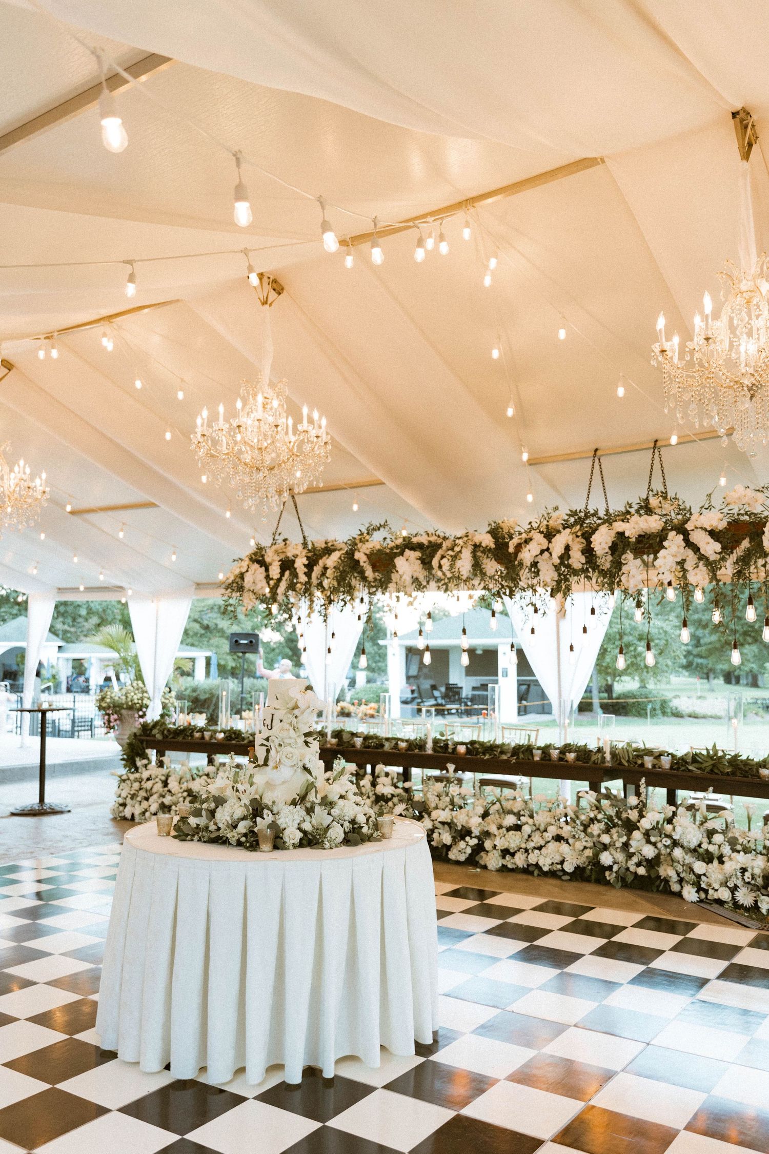 Luxurious wedding reception tent with chandeliers and floral arrangements.