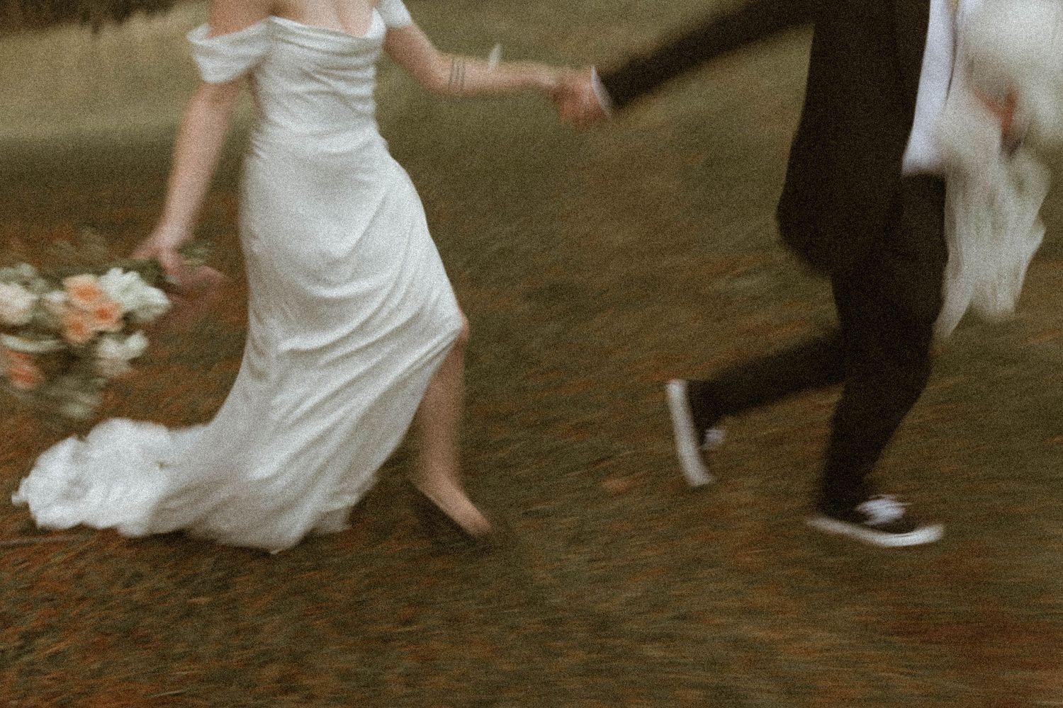 Motion blur captures newlyweds dancing, with bride's white dress and groom's sneakers visible.