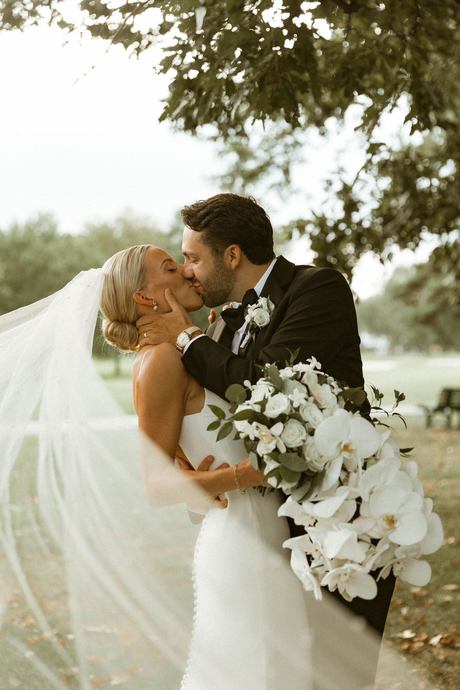 A romantic wedding couple shares an intimate moment with a stunning white orchid bouquet.