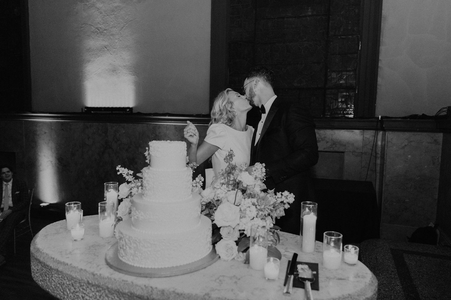 Wedding reception setup with elegant white cake and table decorations.