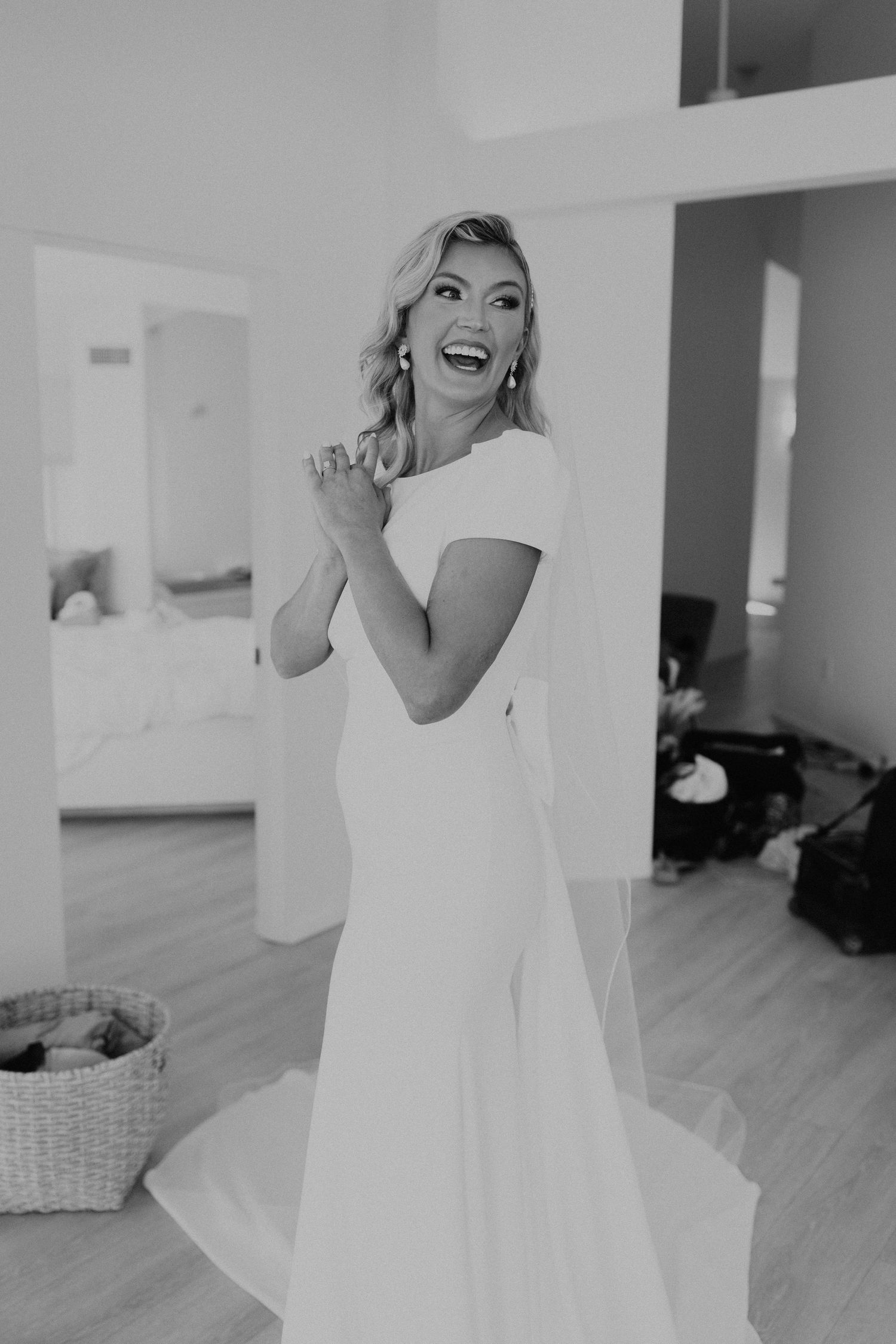 Joyful moments captured while getting ready in white bridal suite.