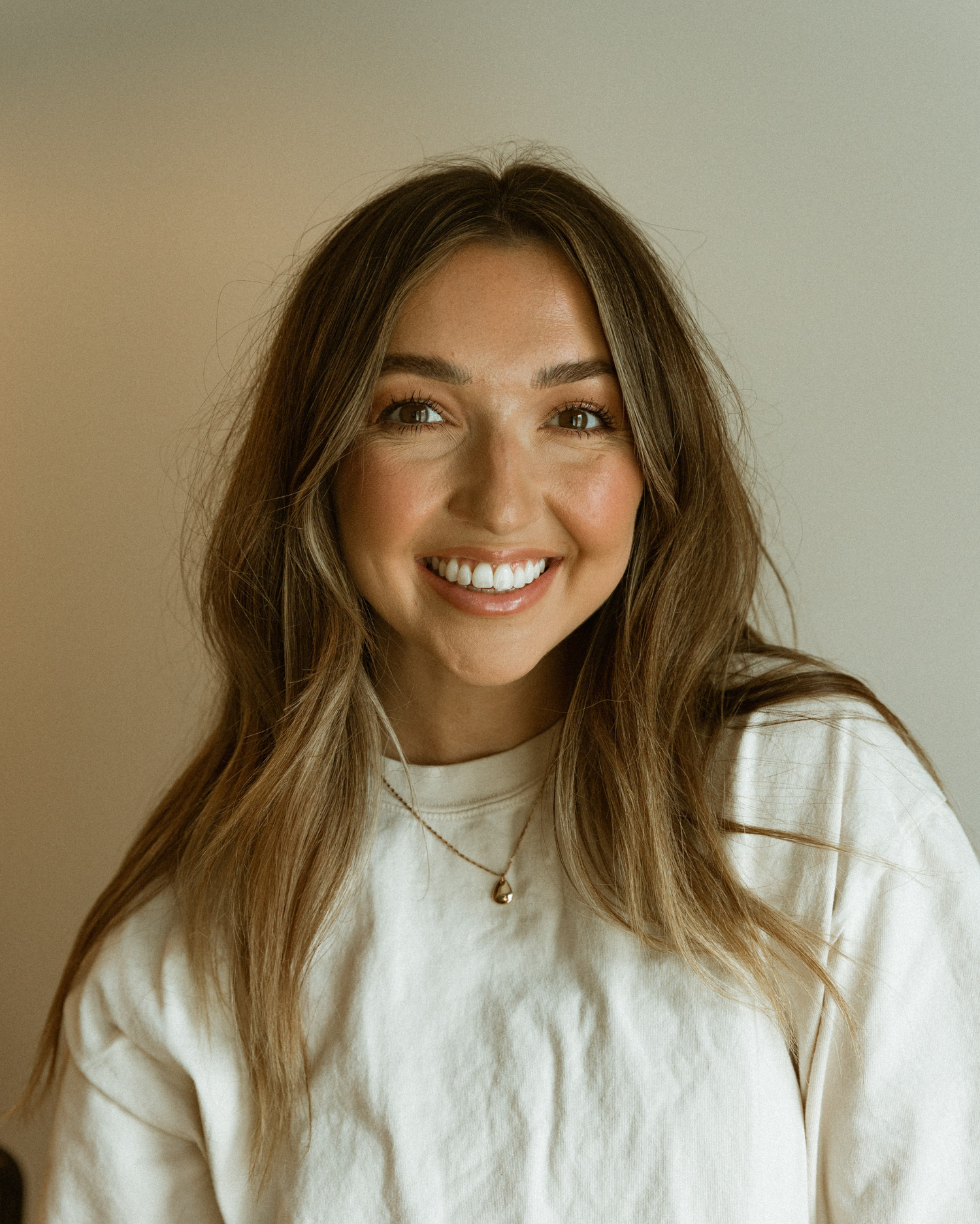Portrait series in white turtleneck showing natural expressions against light background.