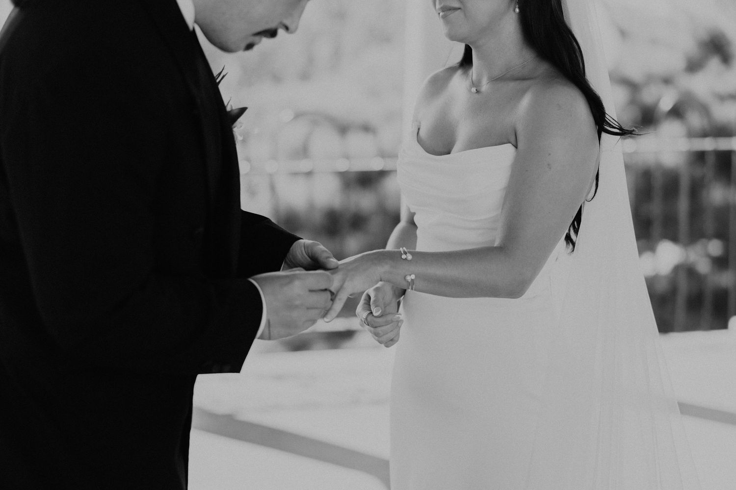 Close-up of hands exchanging rings during an outdoor wedding ceremony.