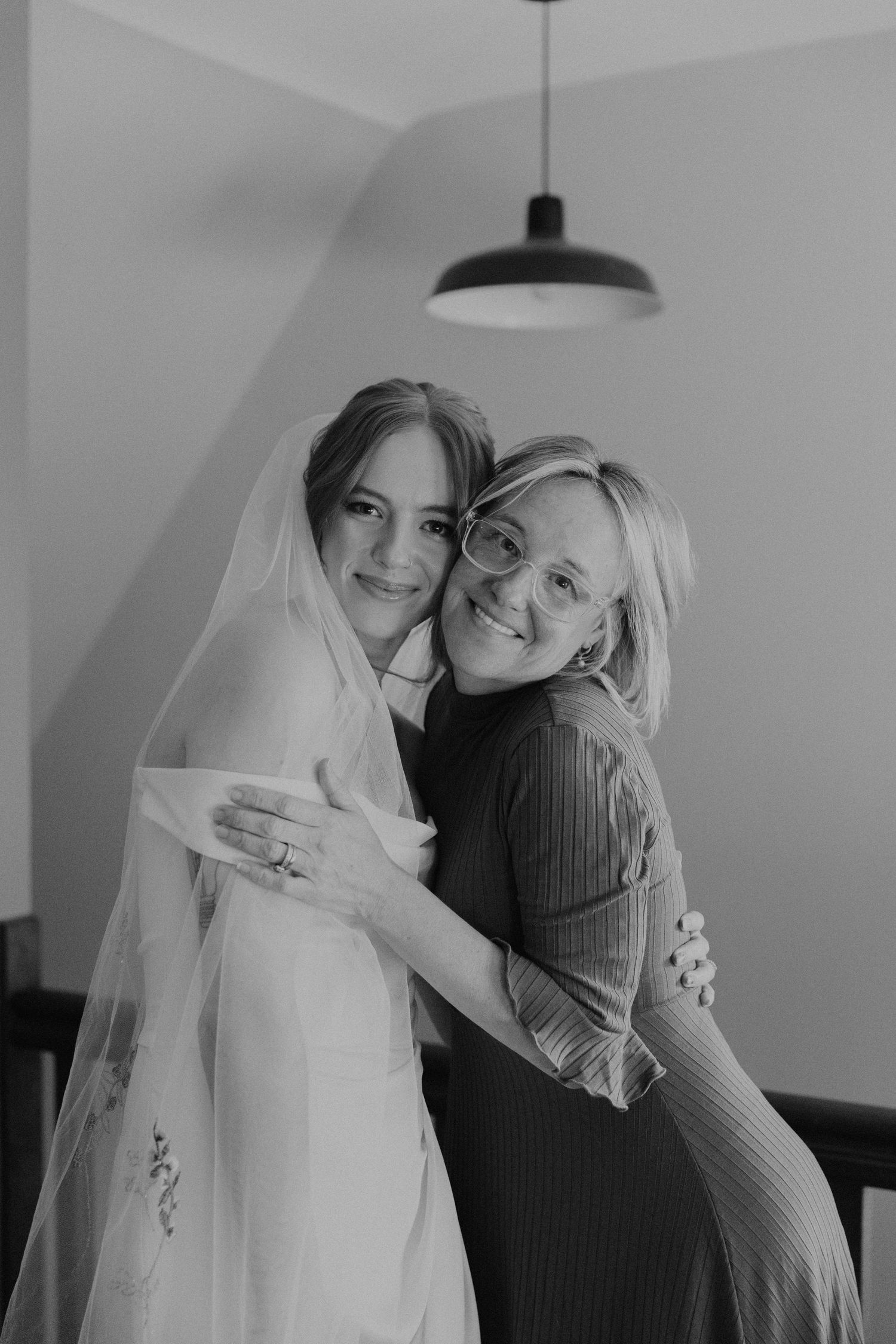 A touching moment between bride and loved one sharing an embrace in black and white photography.