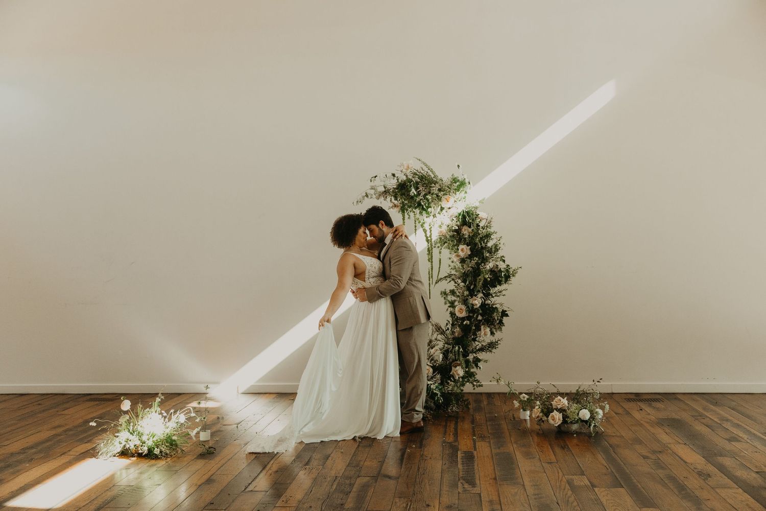 Minimalist wedding scene in bright white room with floral arrangements and natural light.