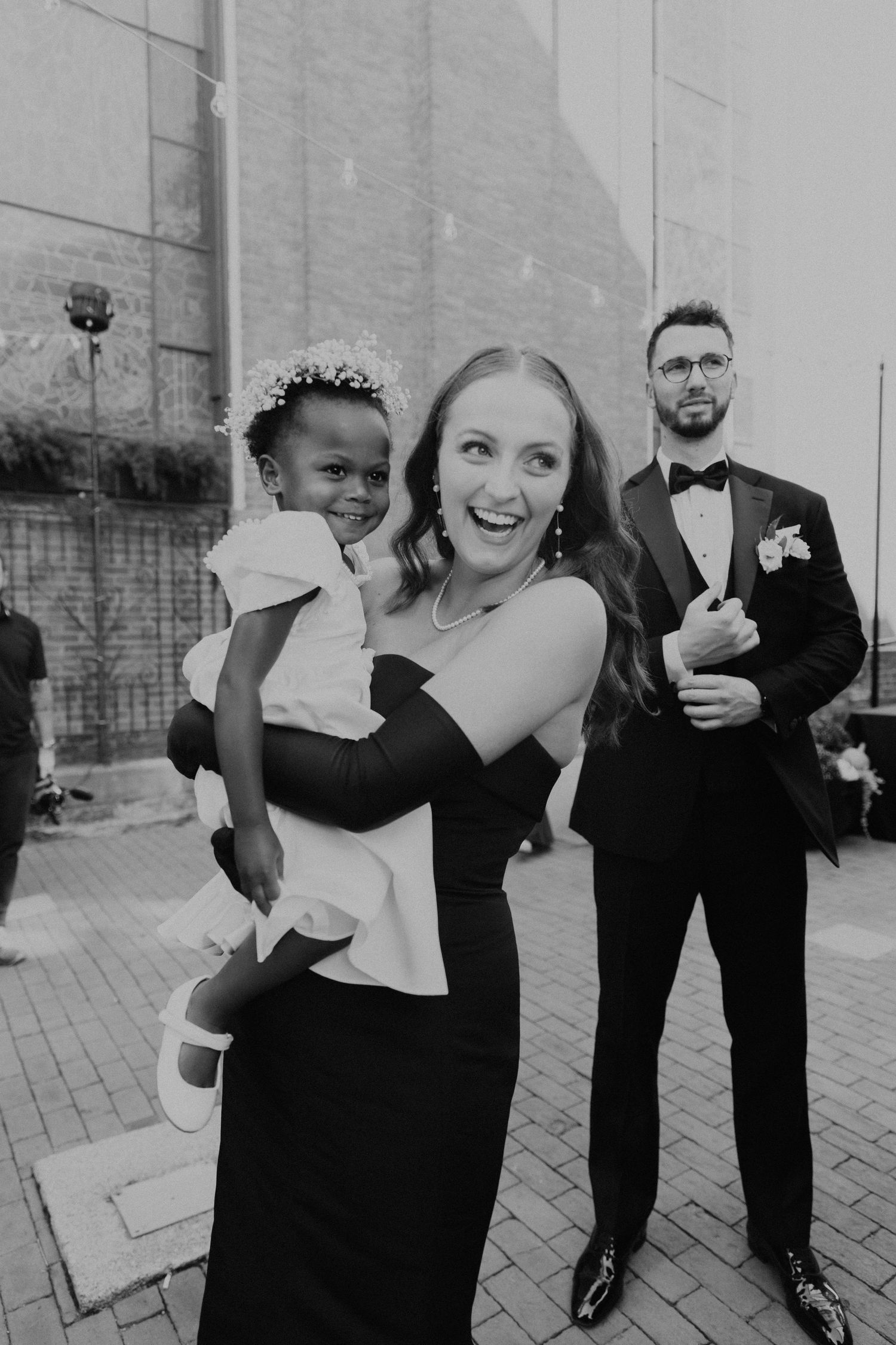Wedding party members sharing candid laughs during formal portrait session.