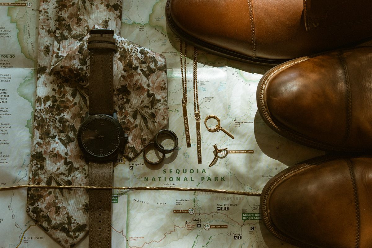 Flatlay of brown leather boots, watch, and vintage keys on an aged map.