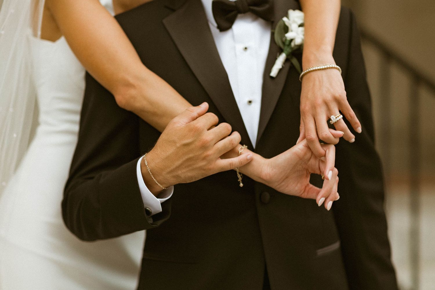 Close-up details of formal wedding attire showing hands and formal wear.