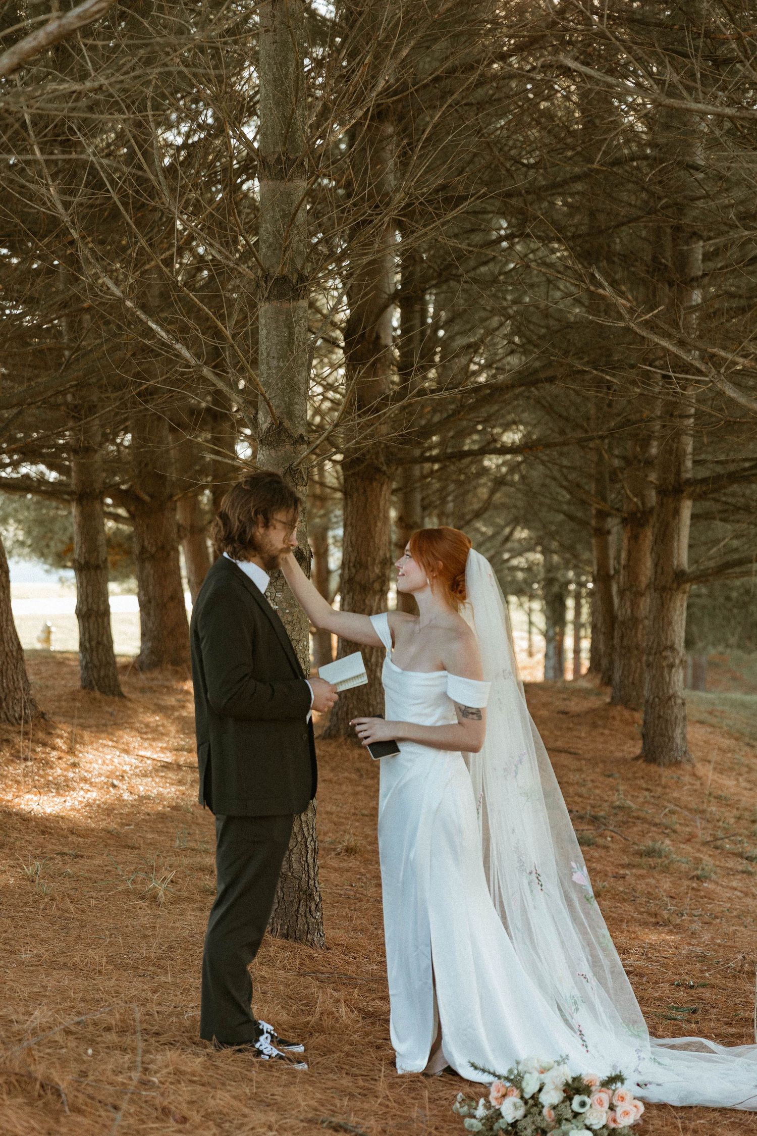 A couple exchanges vows in a sunlit forest setting during their outdoor ceremony.