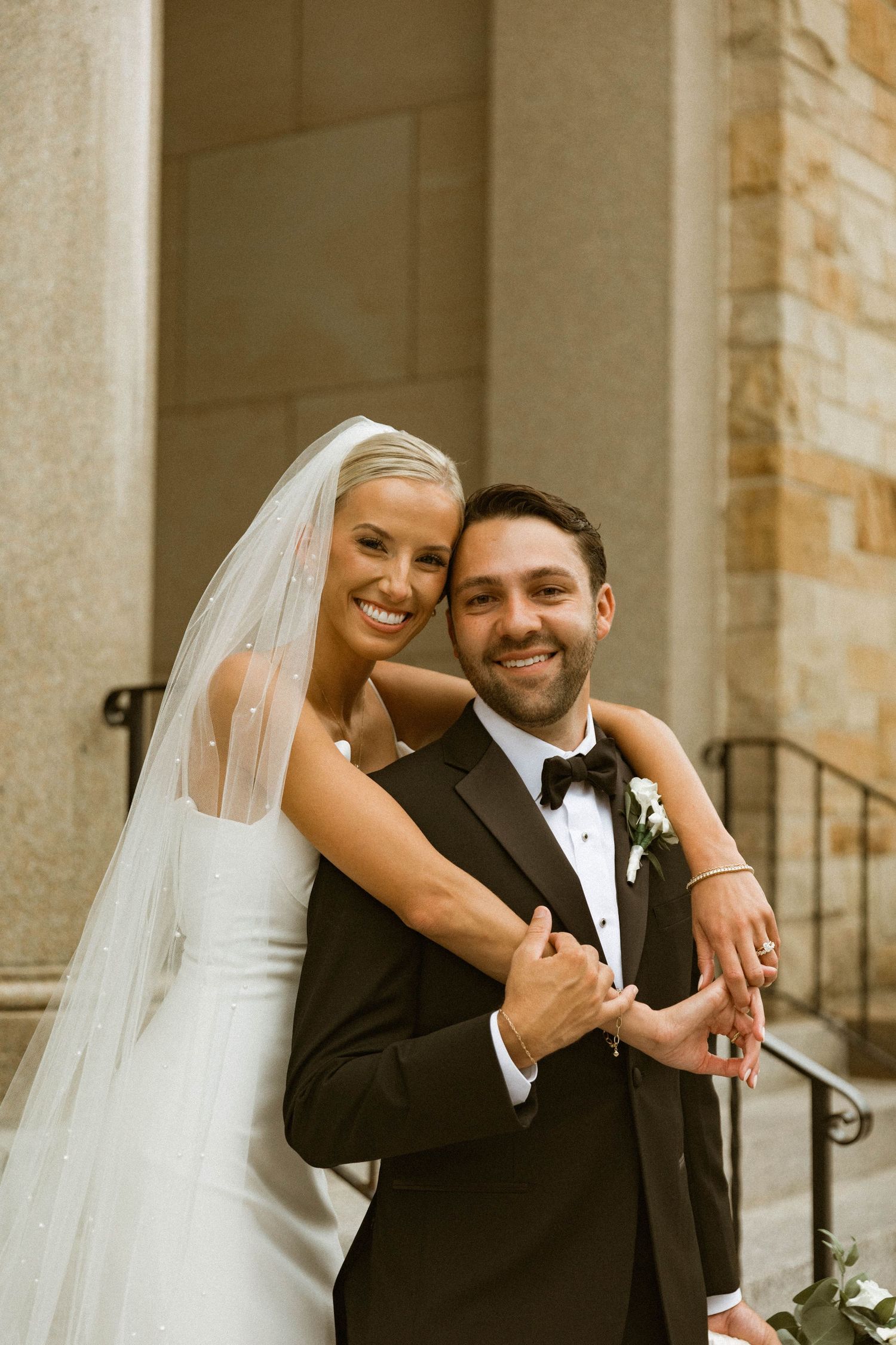 Joyful wedding couple embracing outdoors in formal attire.