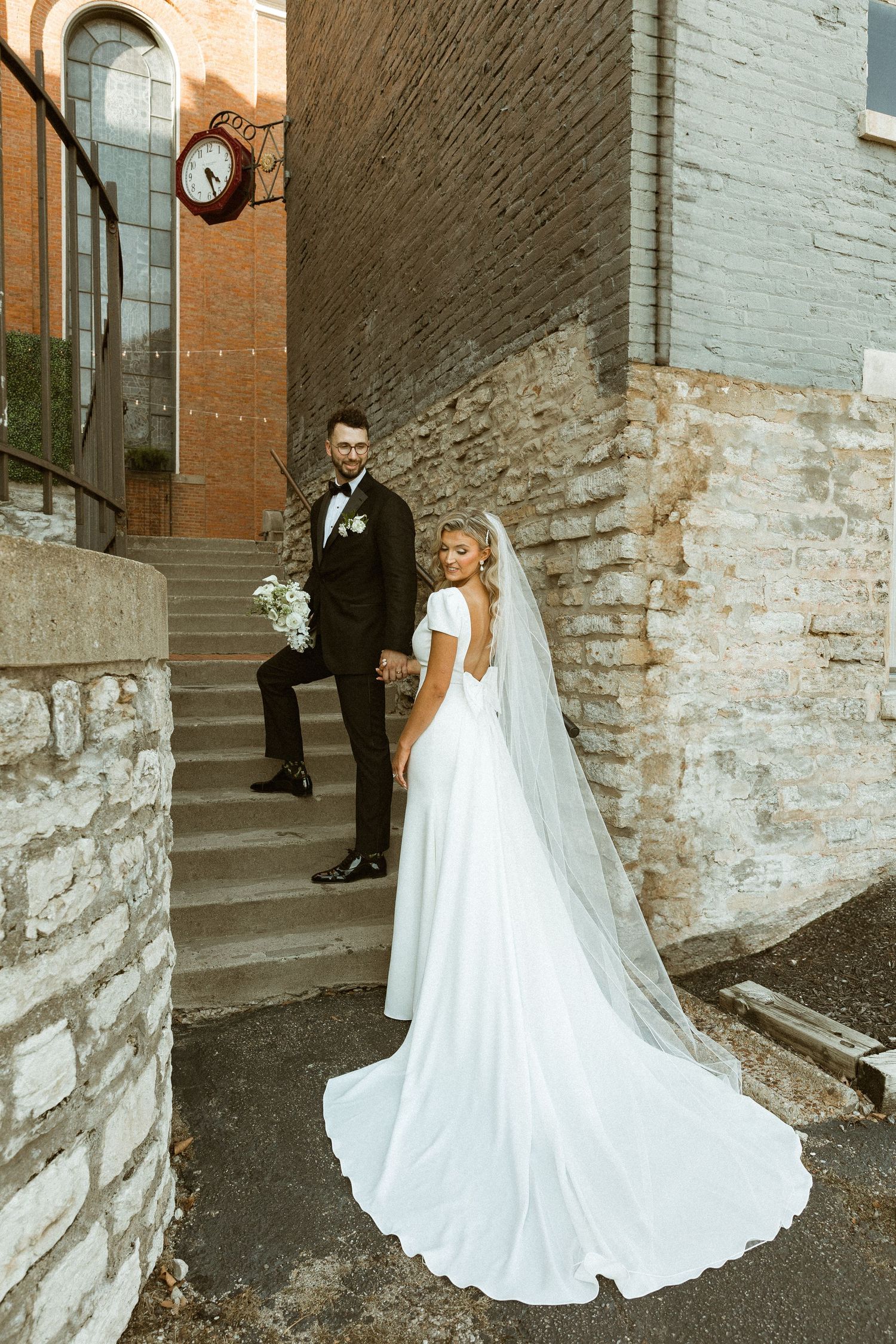 Wedding couple poses near rustic brick and stone walls during their outdoor photoshoot.
