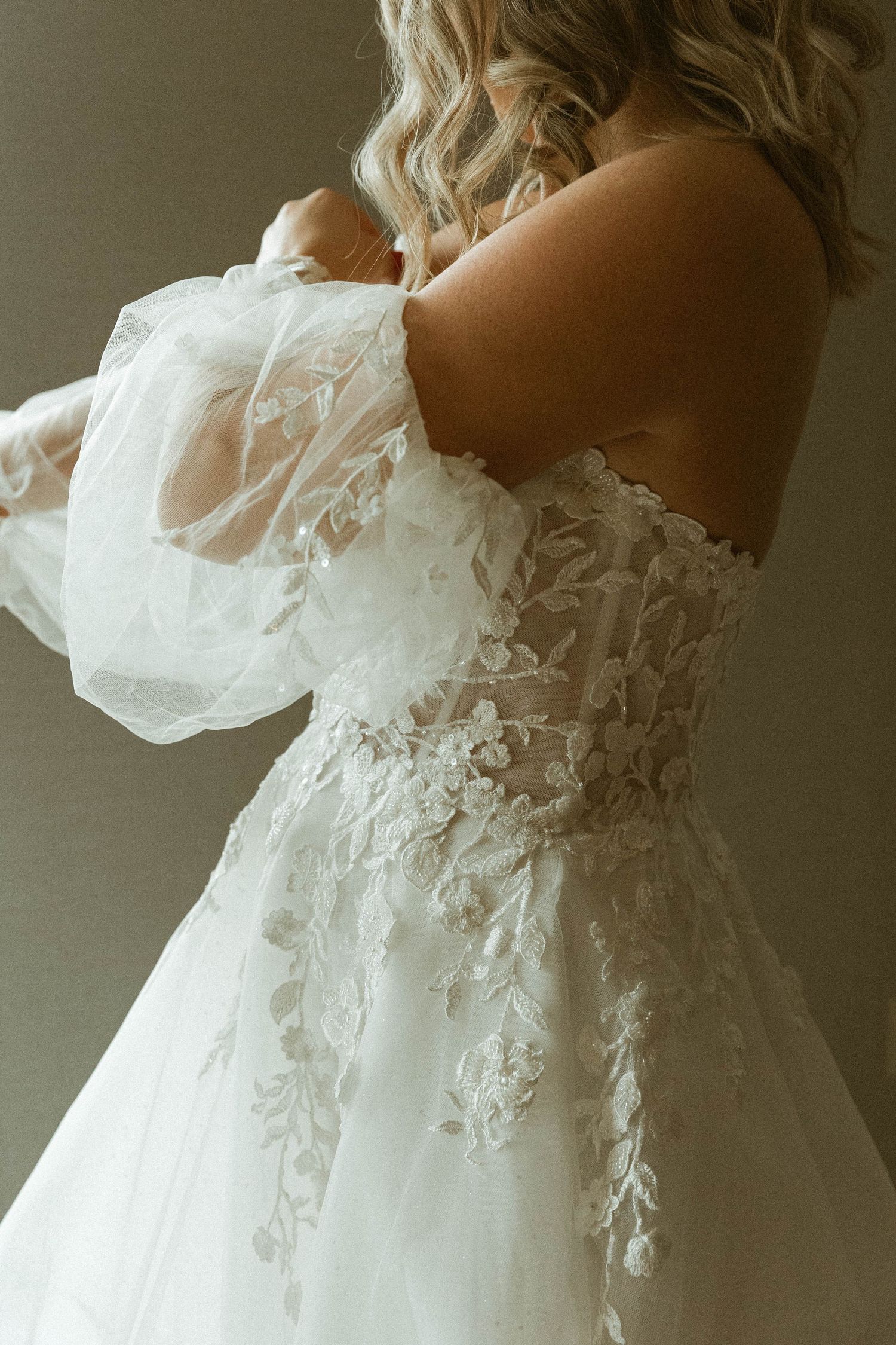 Close-up detail of a white lace wedding dress with off-shoulder design.