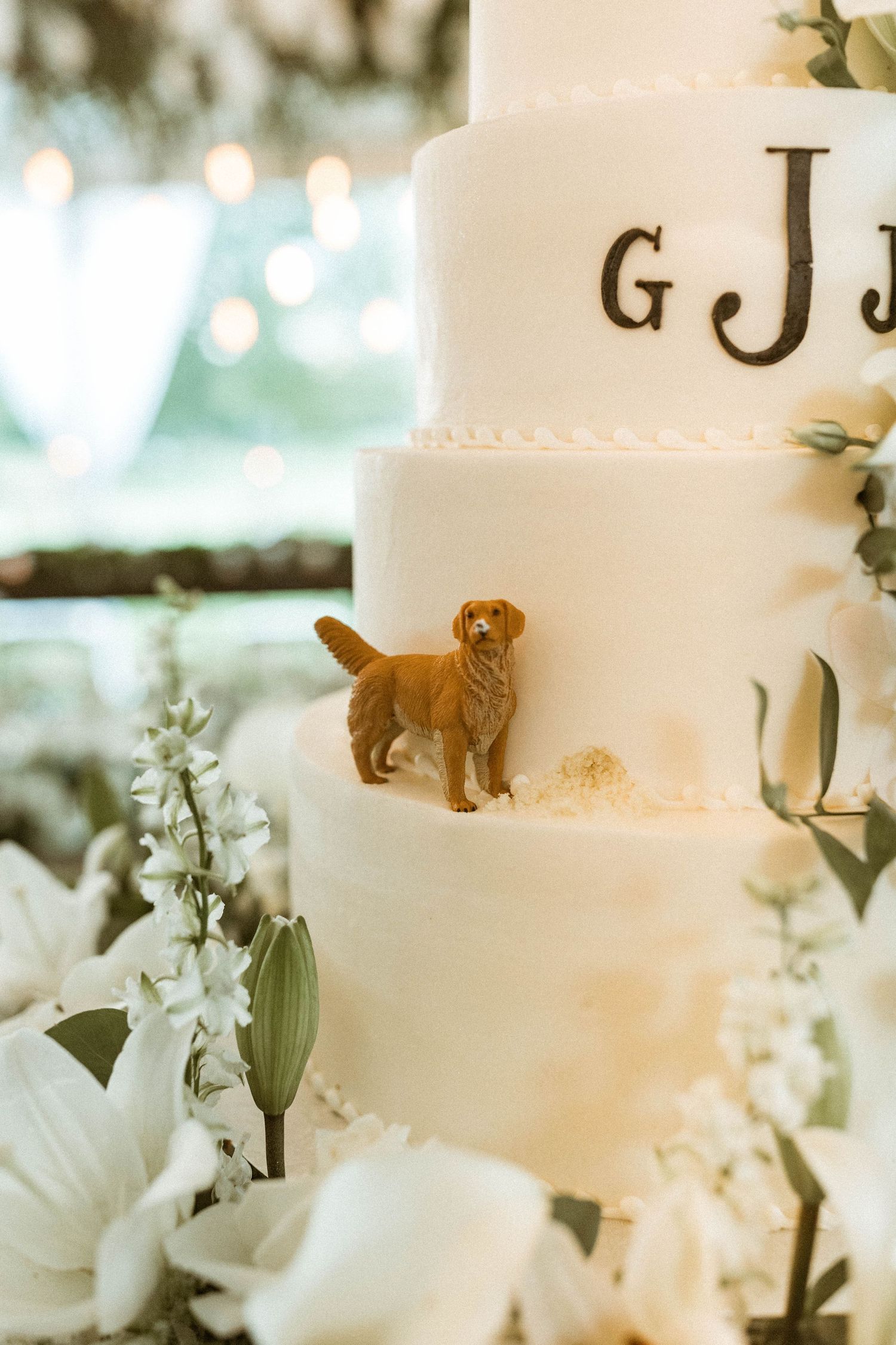 White tiered wedding cake with golden retriever figurine and monogram details.