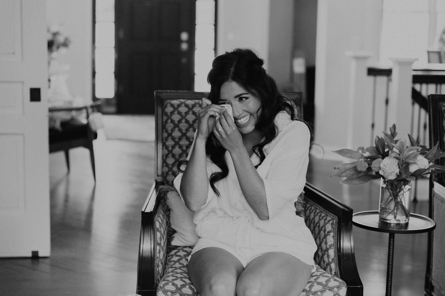 Black and white photo of someone in a robe having an emotional moment while getting ready.