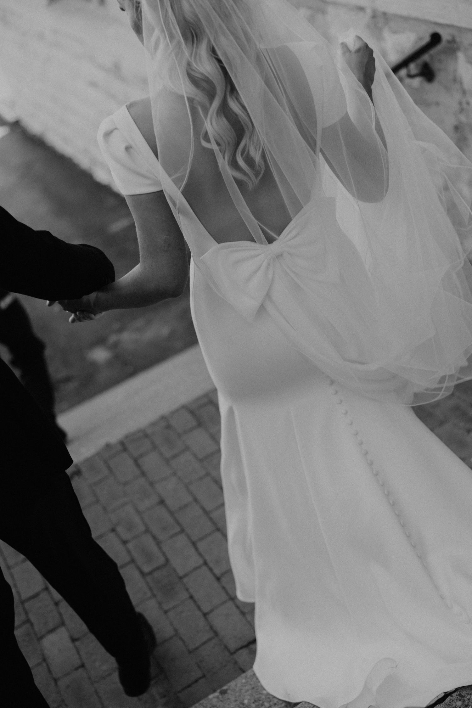 Detail shots of a flowing white wedding dress train on a stone walkway.