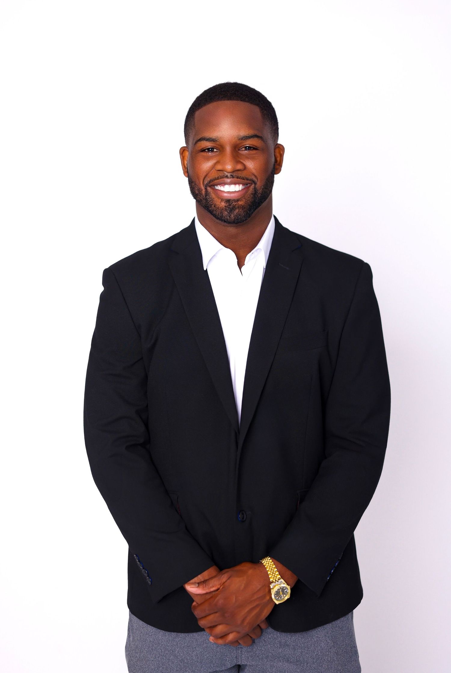Professional studio portraits of a person in a black suit jacket showing different expressions.