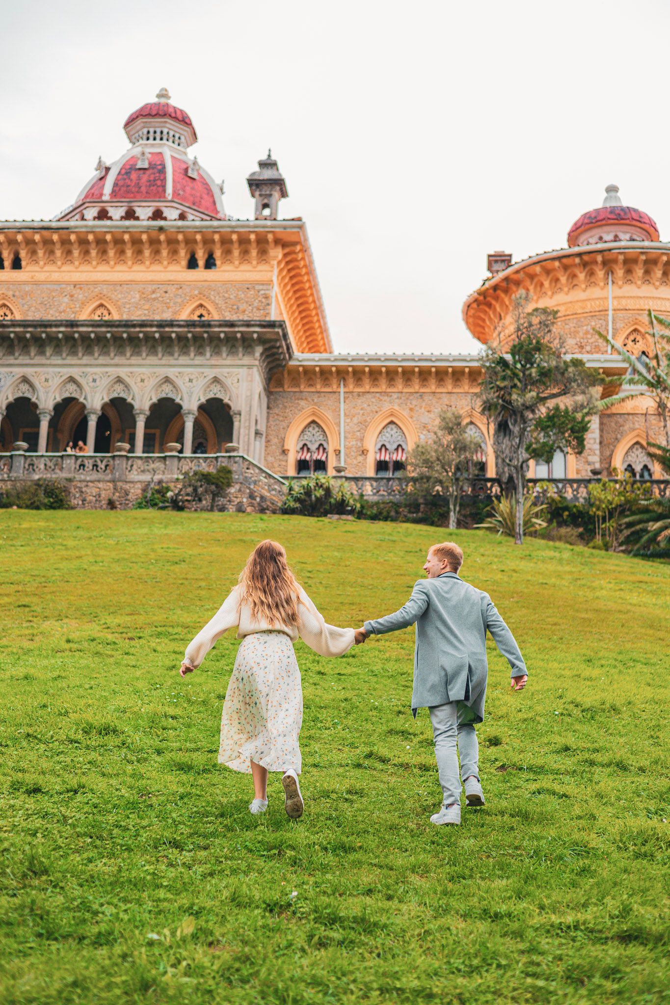Jardim do Palacio monserrate em sintra, jovem casal felizes correndo no gramado em uma sessão de fotografias de casal, pedido de casamento.