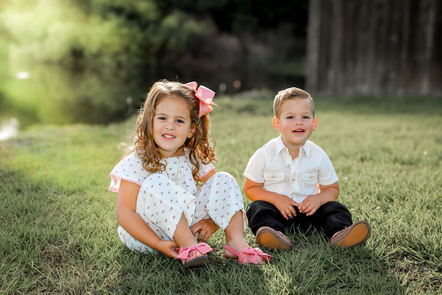 Children playing together on grass wearing matching outfits on a sunny day.