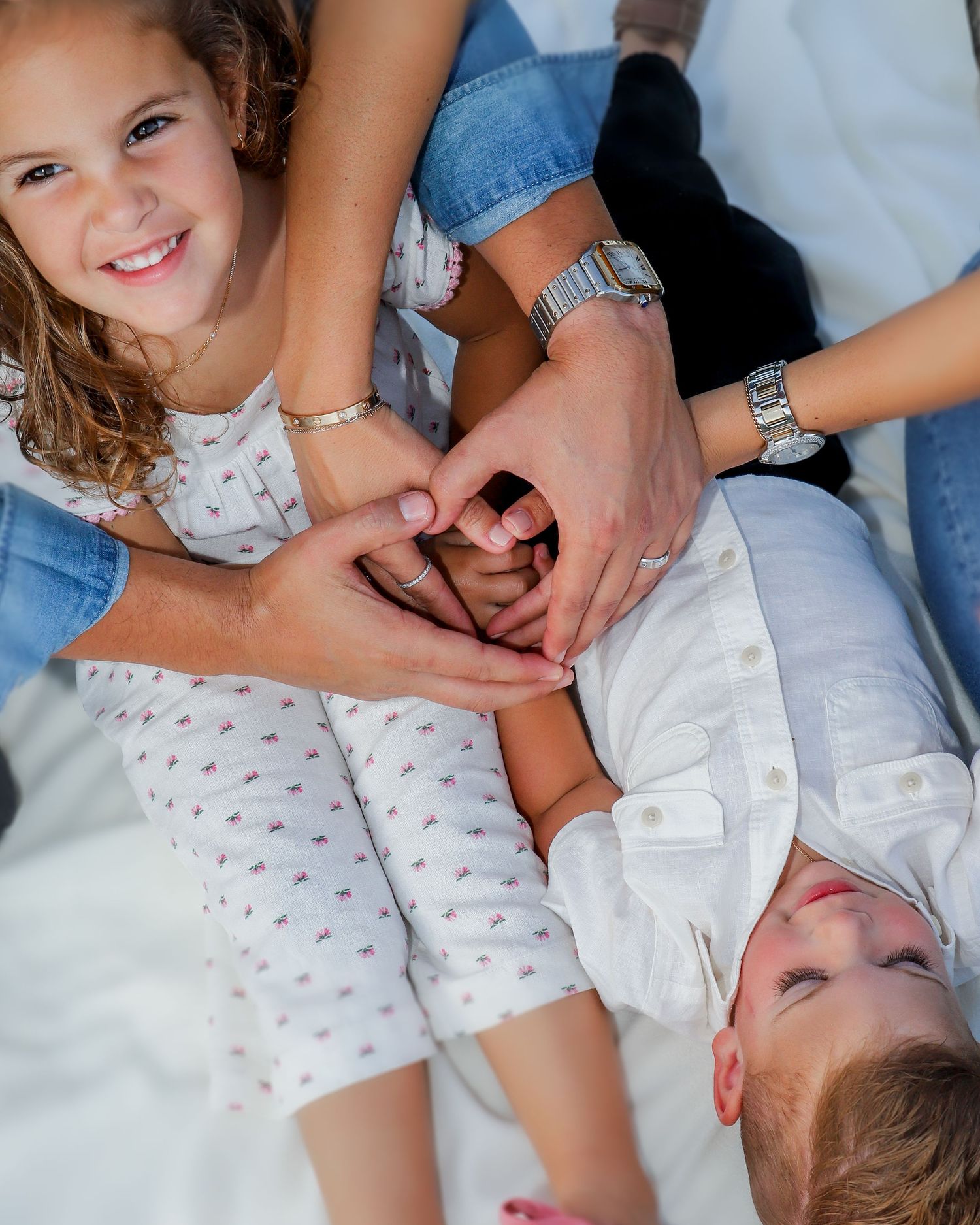 Overhead view of hands forming heart shape while laying on blanket outdoors.